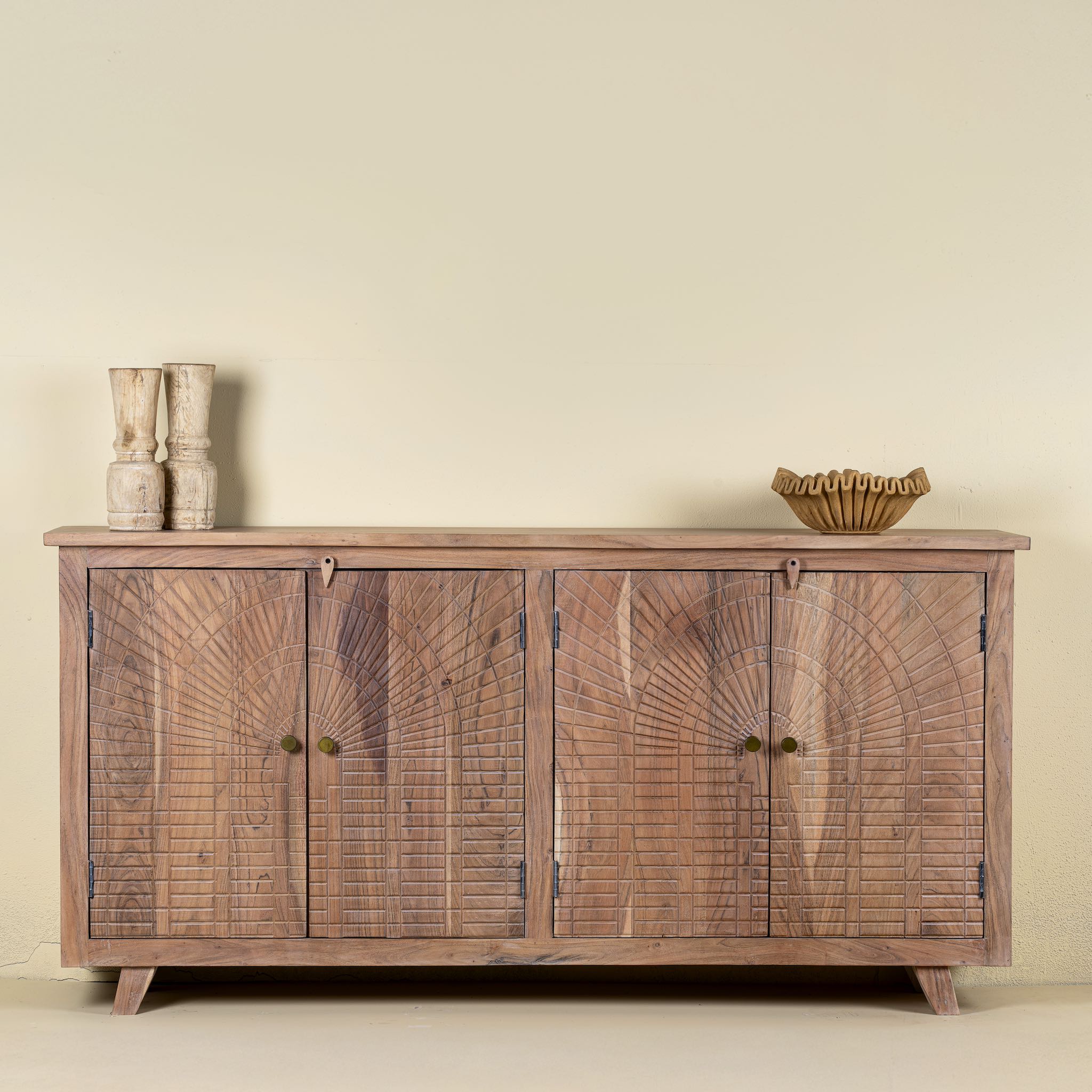 Front view of a sideboard with artisanal inspired carvings on 4 doors made of acacia wood.