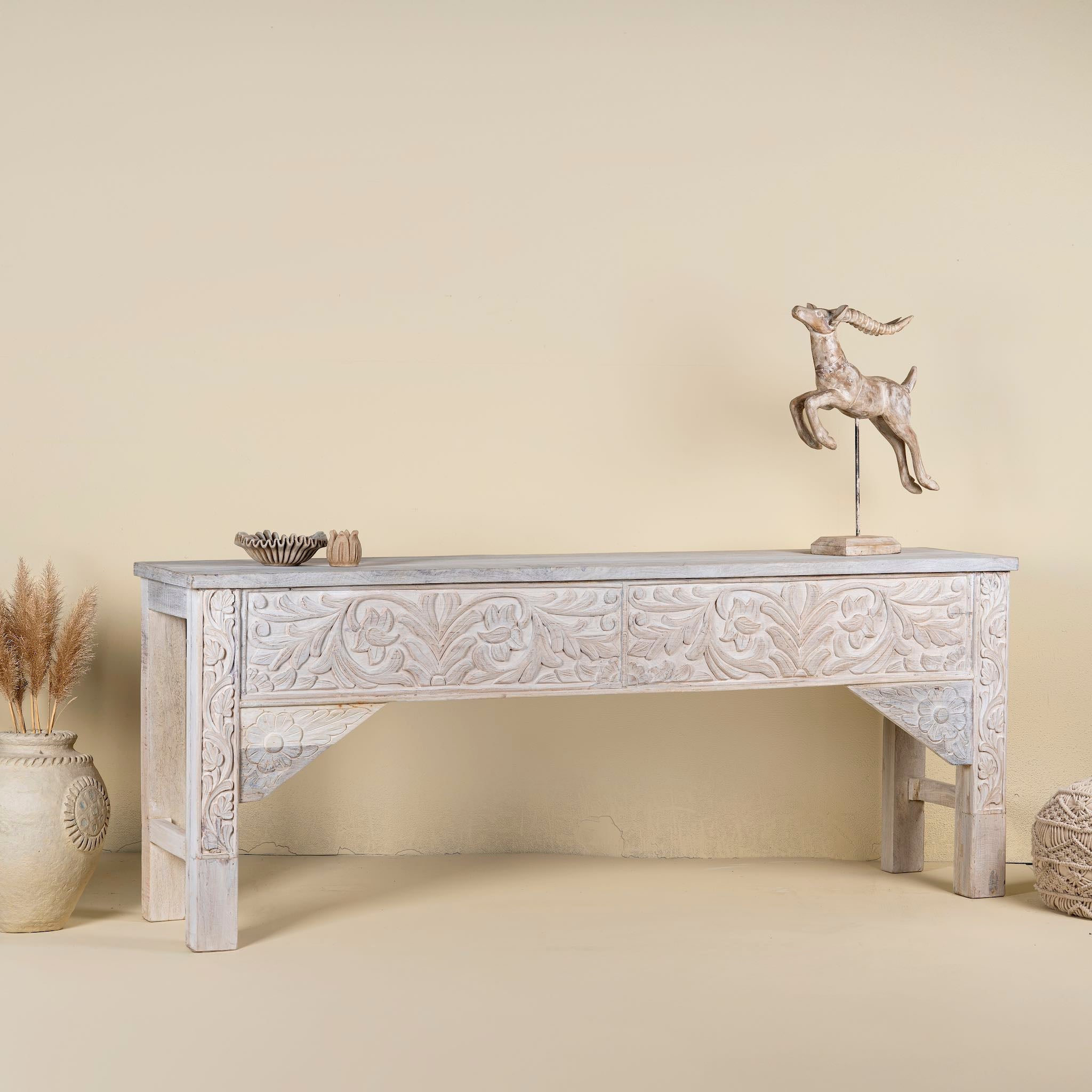 Side angle image of a hand-carved whitewashed reclaimed wood console table with floral details; vintage home decor with rustic and bohemian charm, 196 × 44 × 80 cm.