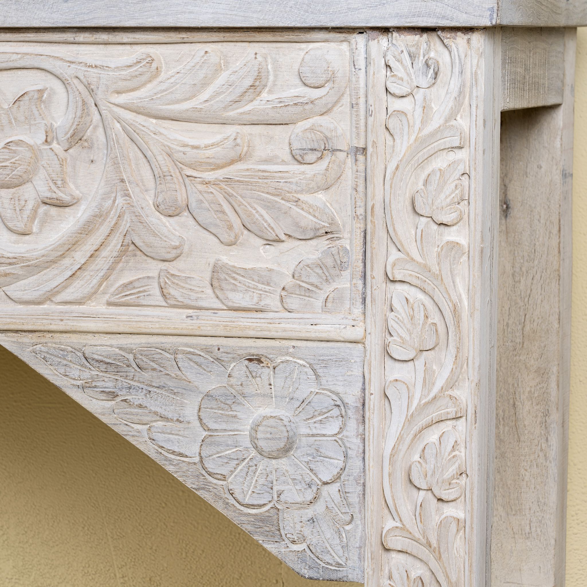 Close up side image of a hand-carved whitewashed reclaimed wood console table with floral details; vintage home decor with rustic and bohemian charm, 196 × 44 × 80 cm.
