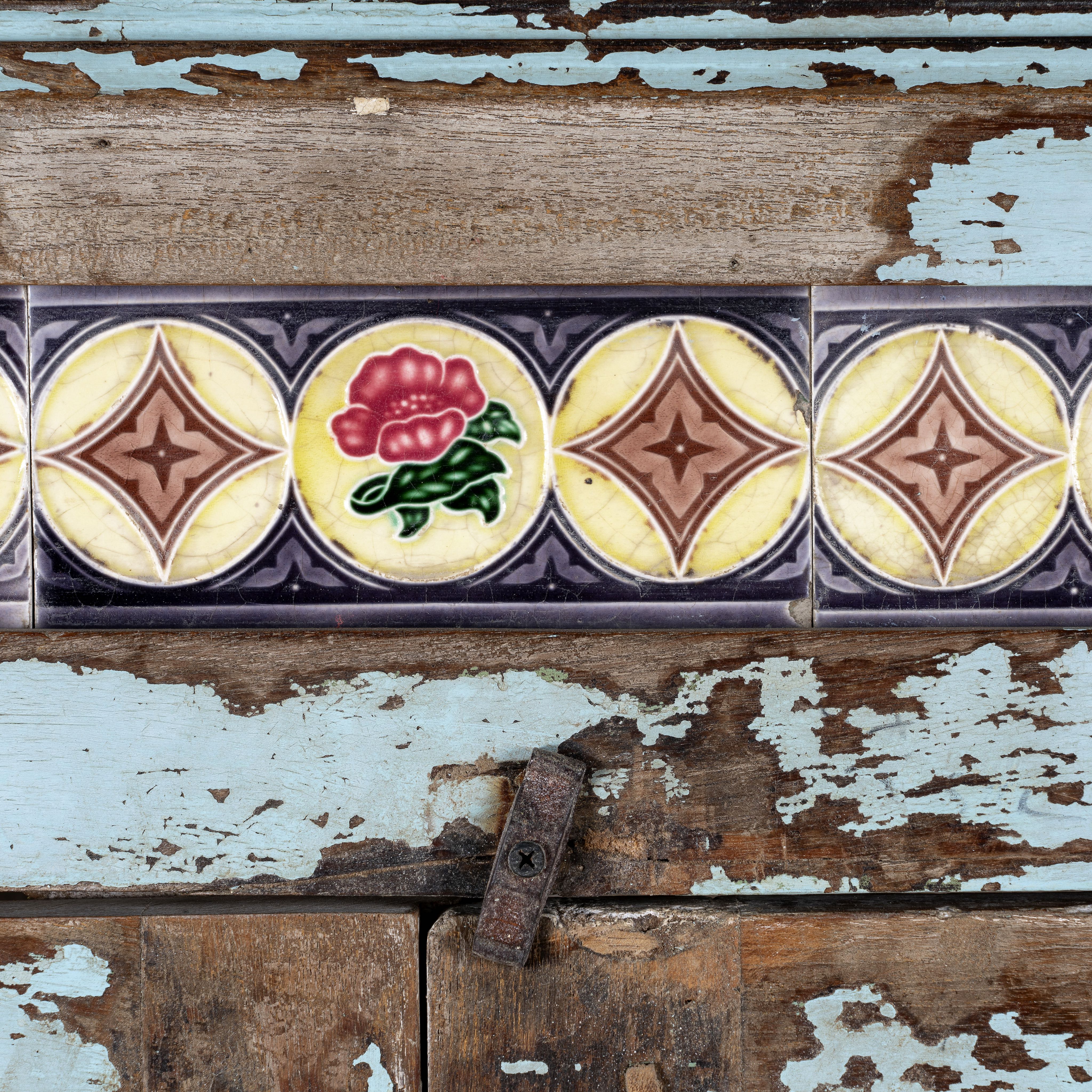 Close up image of a reclaimed teak wood display cabinet with light blue shabby chic finish and ceramic inlays – sustainable teak wood showcase with glass doors.