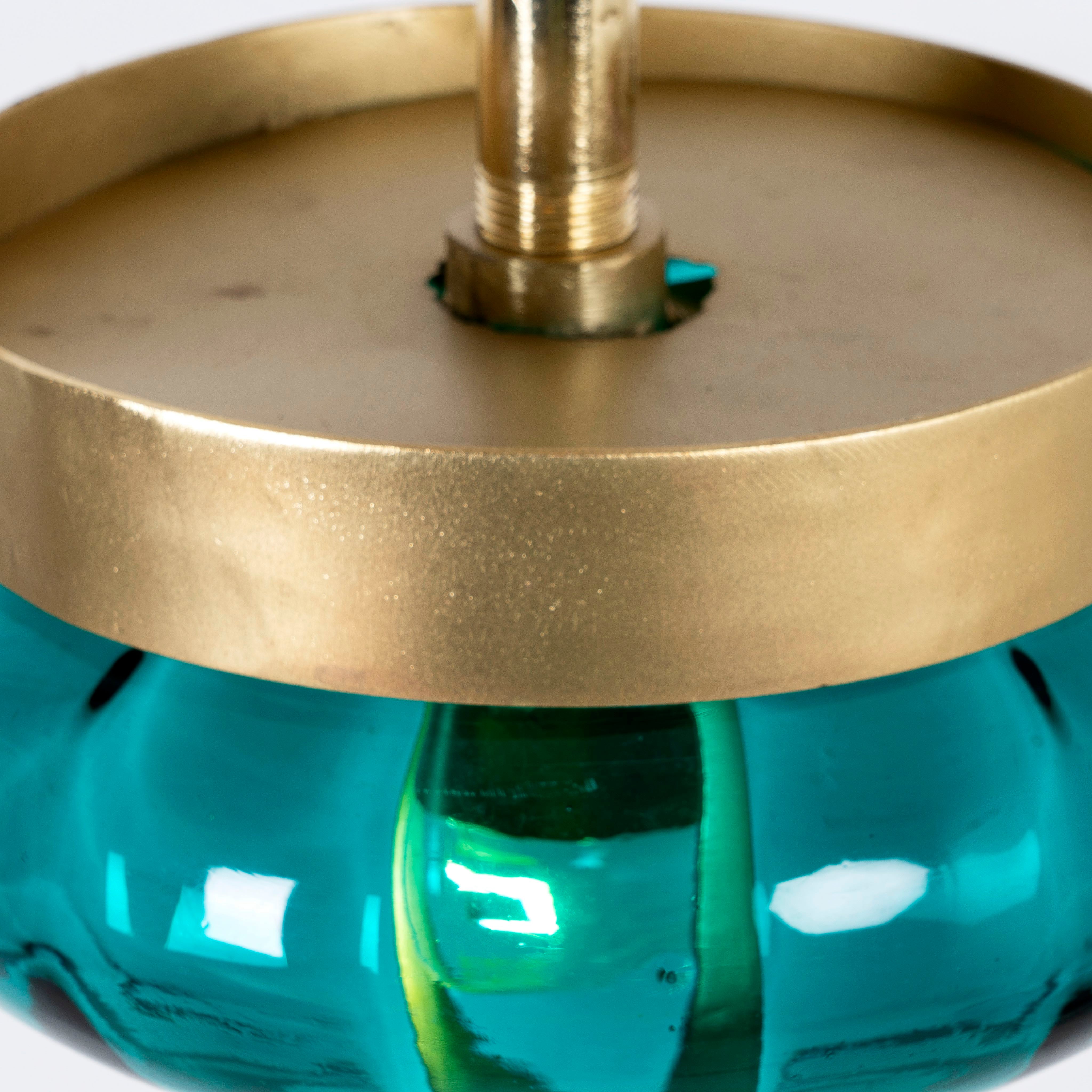 Close up of the top of a retro pendant lamp with large green glass shade and brass-plated iron frame – vibrant glass lamp ideal for dining rooms, living spaces, or bedrooms.