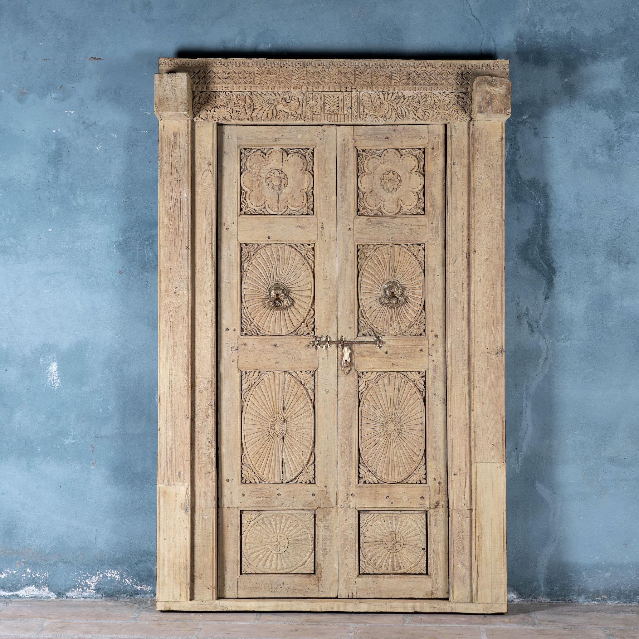 Antique Indian door Akshara in reclaimed teak with brass locks, hand-carved details, extended frame, unique furniture and vintage wall panels, 148 × 30 × 225 cm.