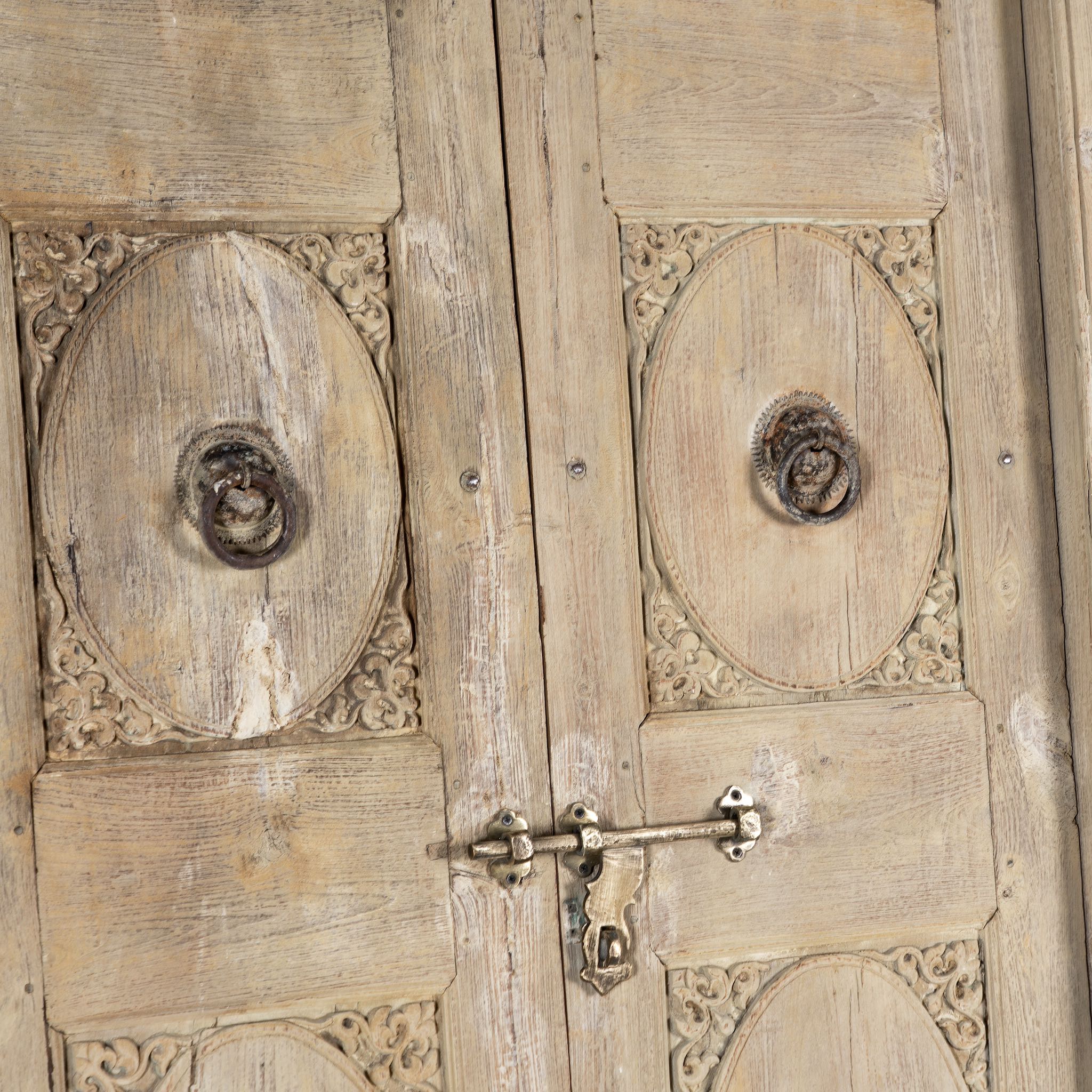 Close up image of a antique Indian door Amaya made of reclaimed teak with brass fittings, hand-carved details, extended frame, usable as entrance or vintage wall panels, 161 × 20 × 250 cm.