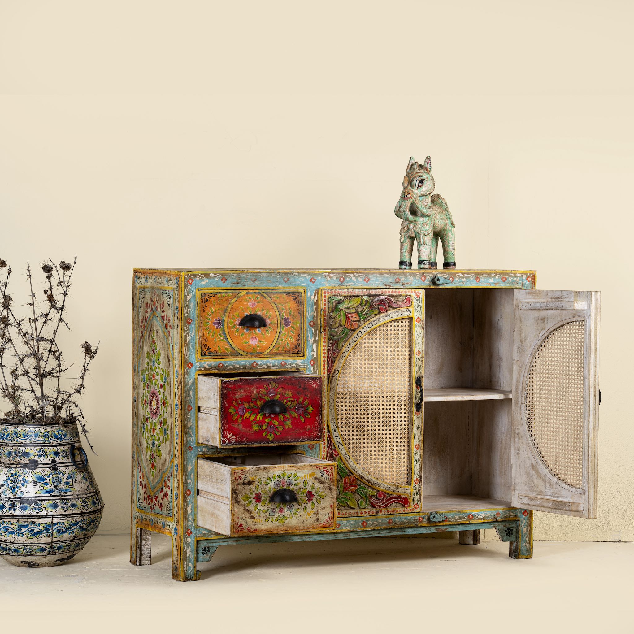 Side angle with open doors of a hand painted sideboard Ashara made of mango wood with rattan inserts; Ibiza-inspired boho chic furniture, 120 × 40 × 92 cm.