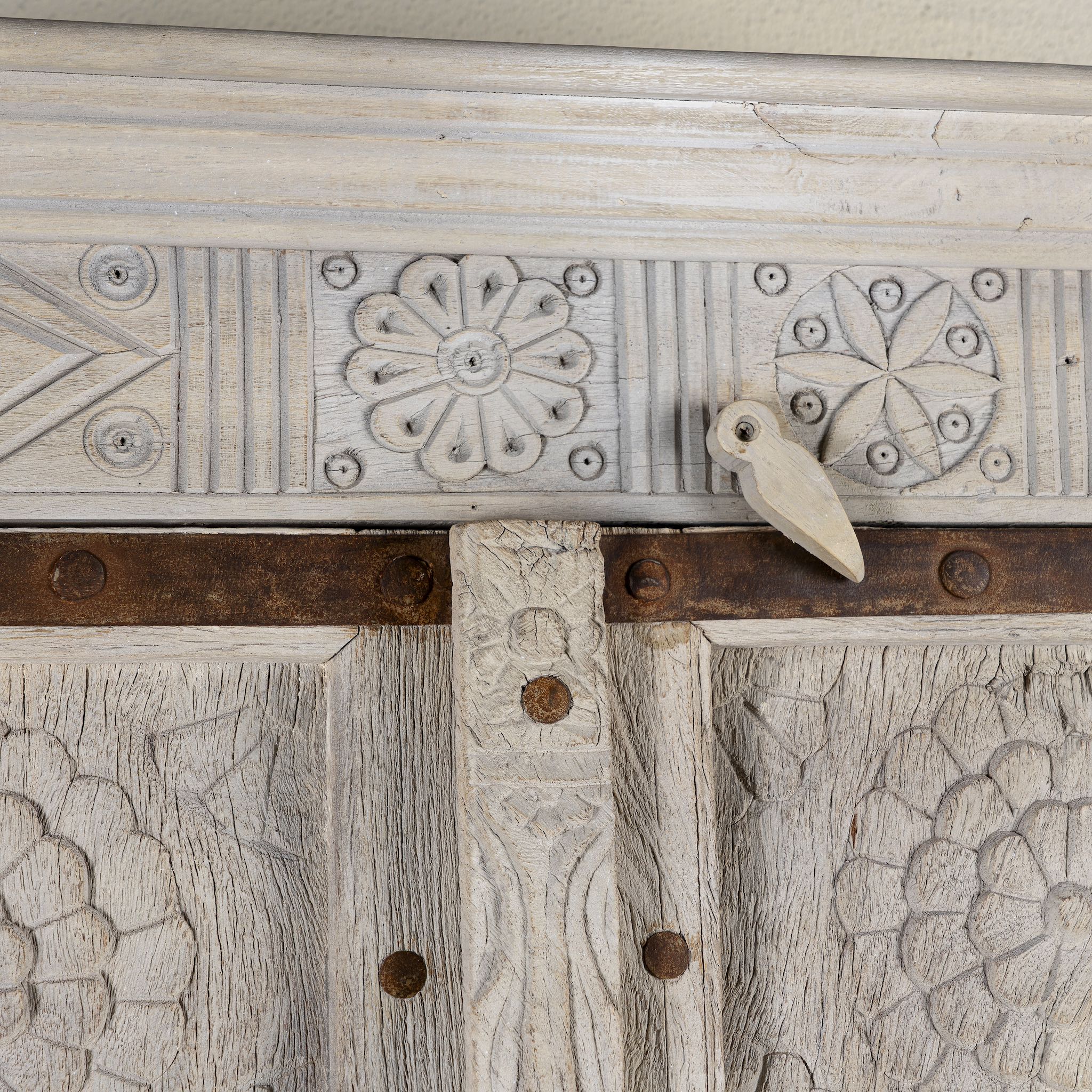 Close up image of a old door cabinet with reclaimed teak doors, floral carvings, and iron accents; artisan teak wood wardrobe with mango wood frame, 100 × 44 × 206 cm.