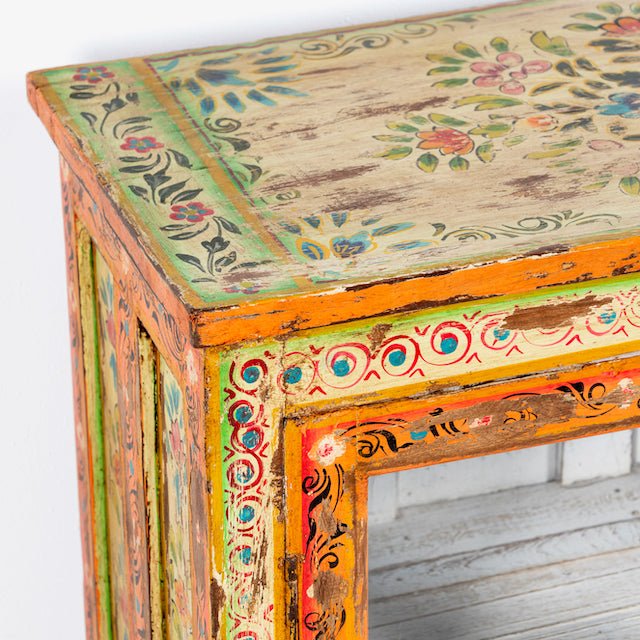 Close up image of a hand-painted teak wood display cabinet with glass doors and vibrant Indian motifs – sustainable furniture with vintage charm and artisanal detail.