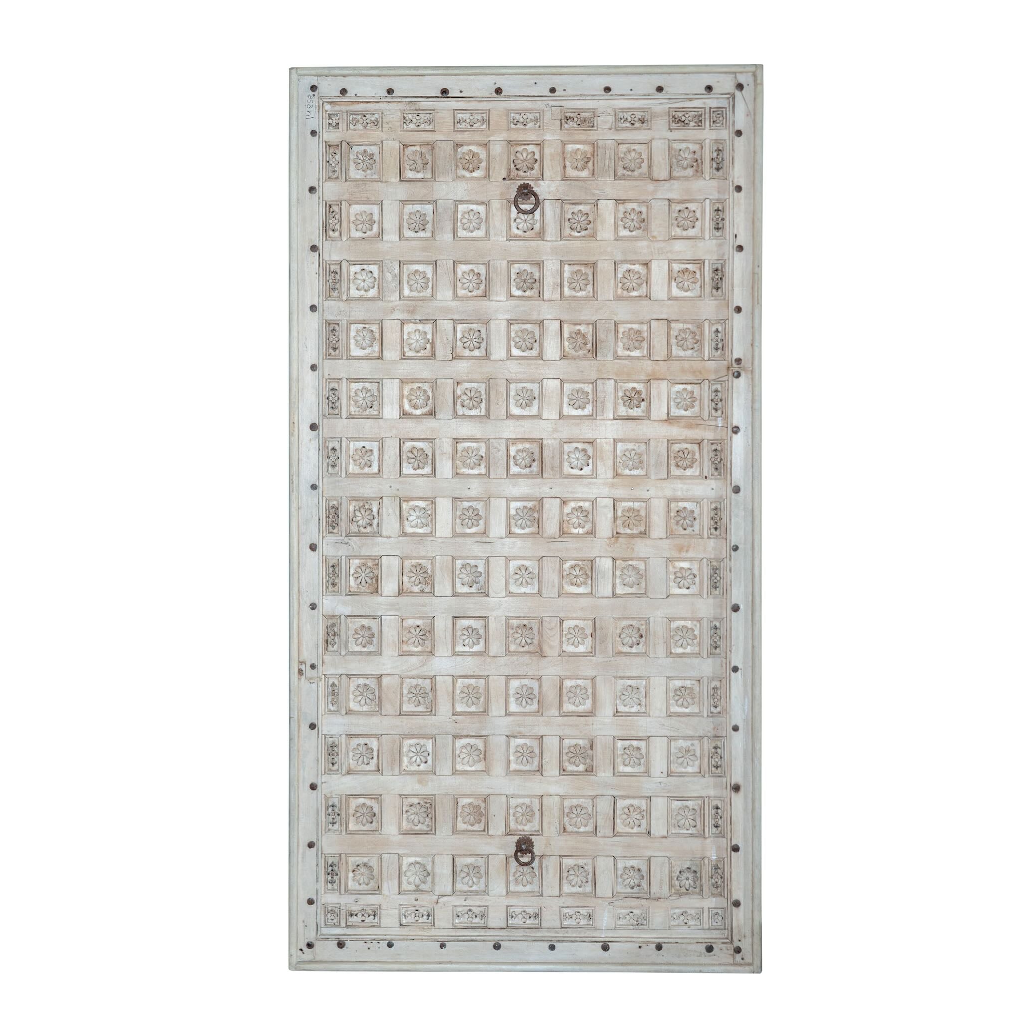 White background image of a Bhuvi hand-carved teak headboard made from an old Indian ceiling door, featuring symmetrical floral panels and a whitewashed finish—an heirloom-style piece of old door headboards and old Indian door furniture.