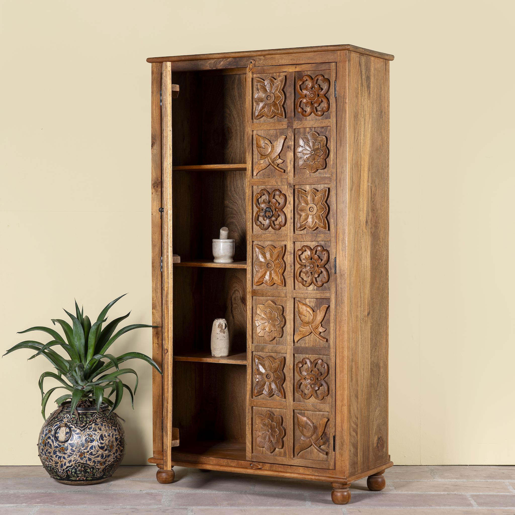 Open door image of a hand-carved mango wood wardrobe with floral motifs; wooden wardrobe in natural finish, 100 × 45 × 190 cm.