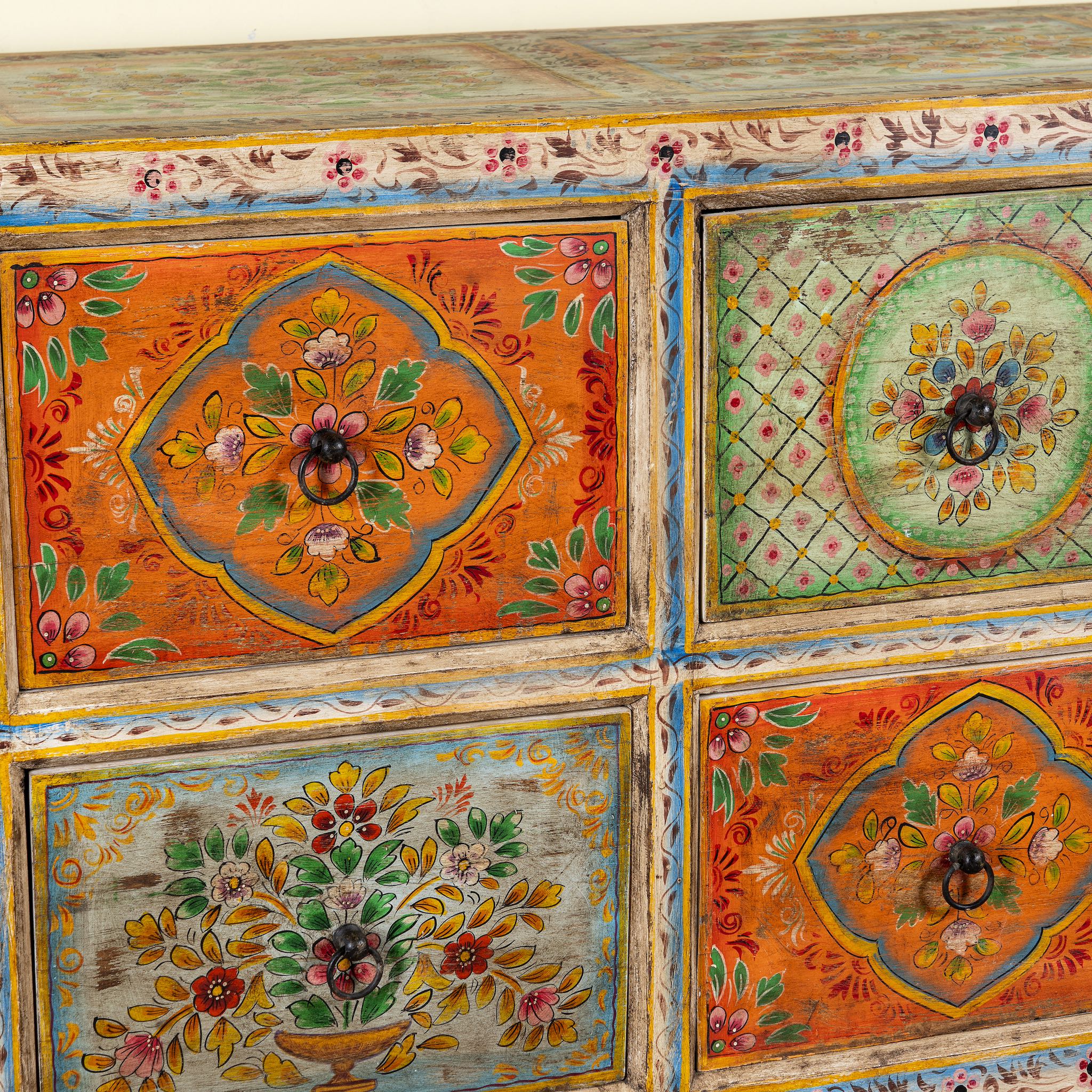 Close up image of a hand painted sideboard with 8 drawers made of natural mango wood; artisanal chest for bohemian interior, 200 × 40 × 90 cm.