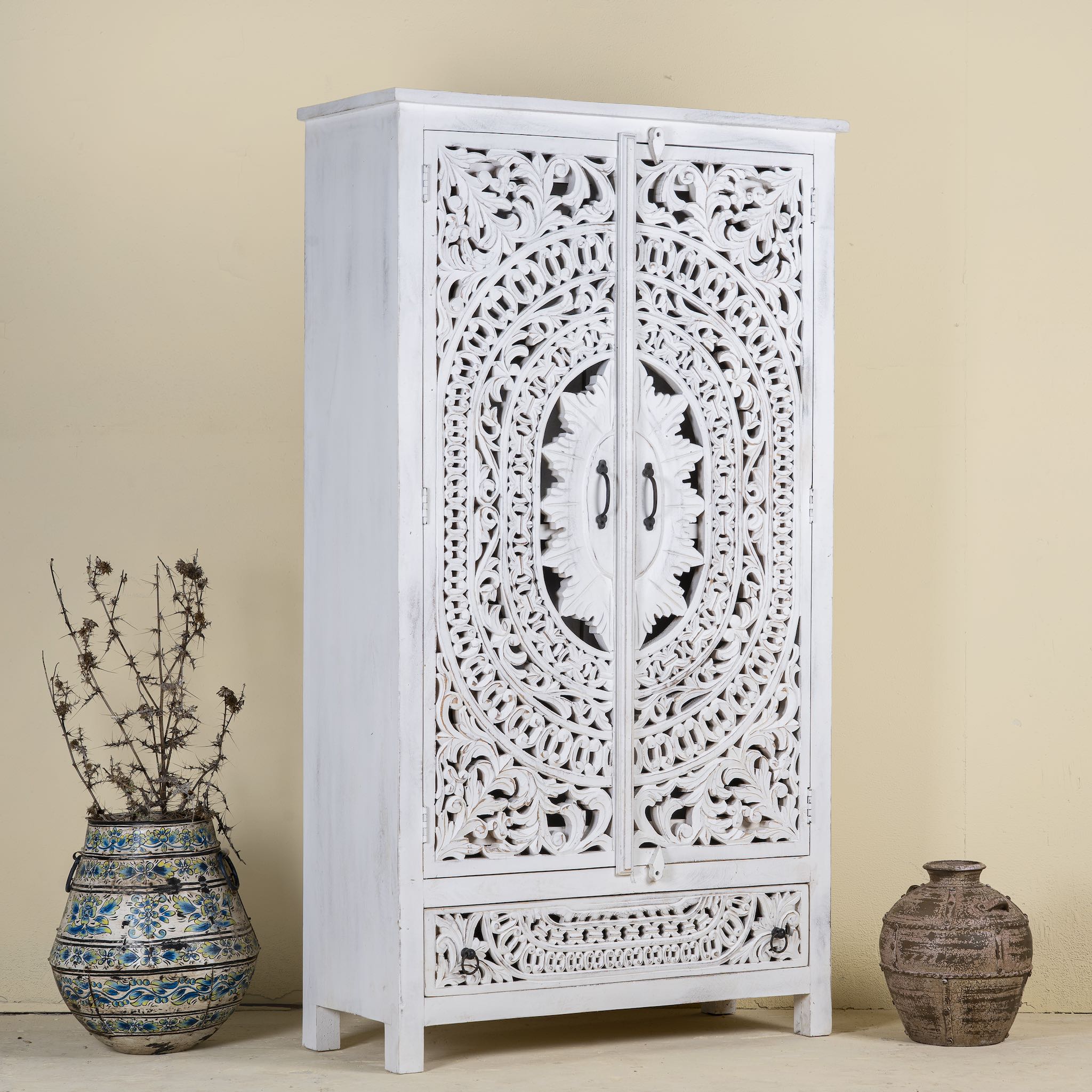 Side angle image of a hand-carved wooden wardrobe in white-wash finish, perfect for a boho chic living room or bedroom storage.