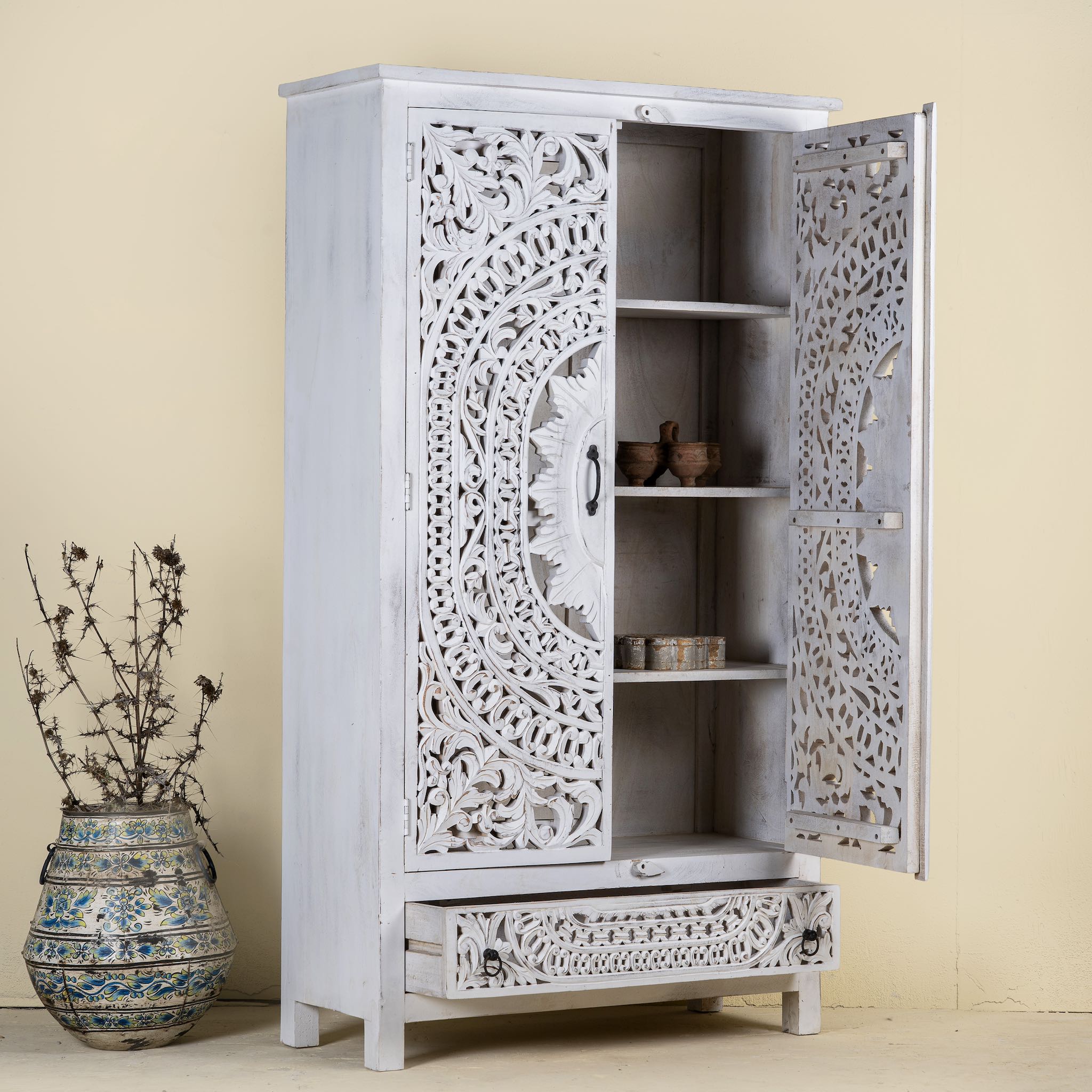 Open door image of a hand-carved wooden wardrobe in white-wash finish, perfect for a boho chic living room or bedroom storage.