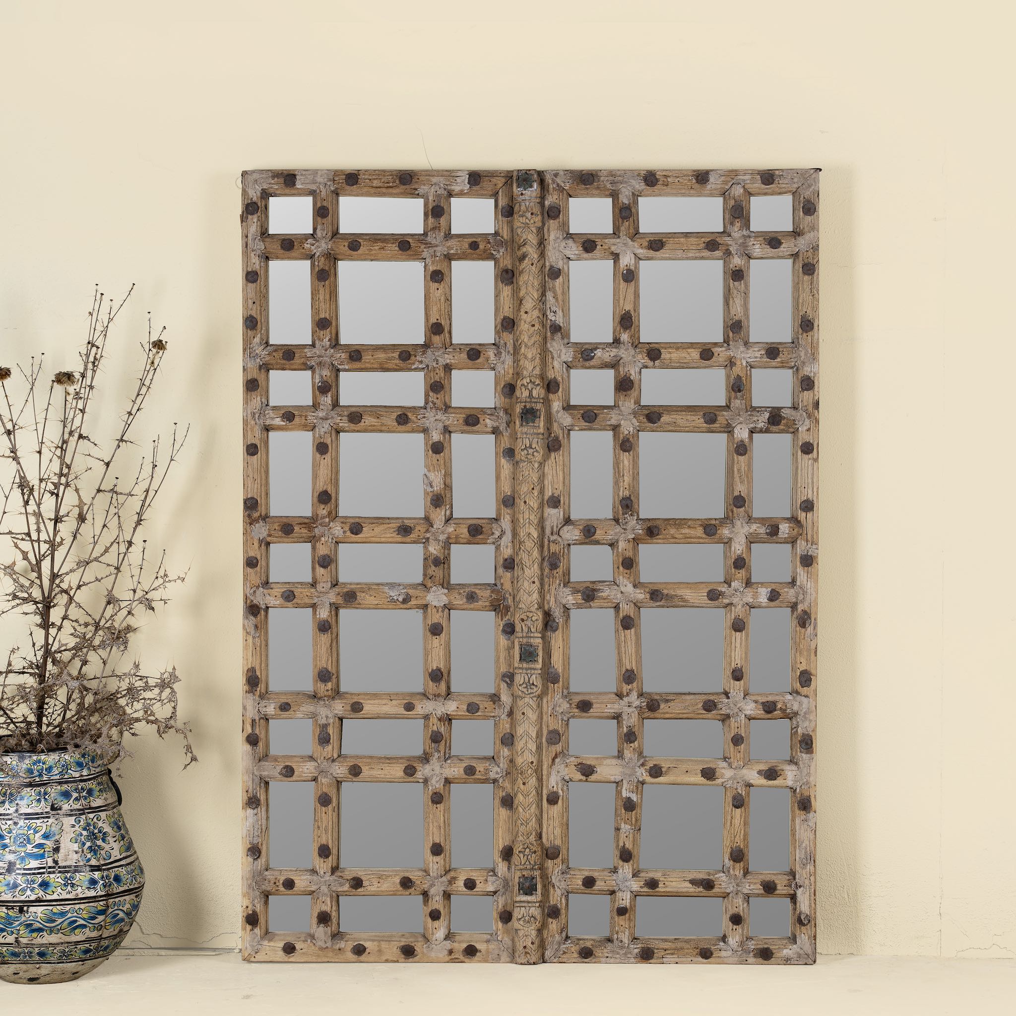 Reclaimed teakwood mirror crafted from an antique Indian door panel, featuring iron accents and mirror inlays – ideal for vintage home decor and heritage-inspired interiors.