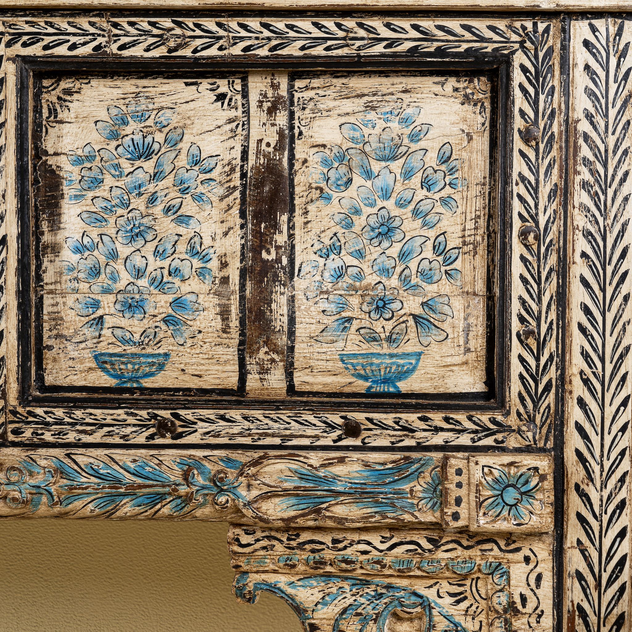 Close up image of a hand painted console table in reclaimed teak with floral motifs and antique distressed finish, 197 × 40 × 82 cm.