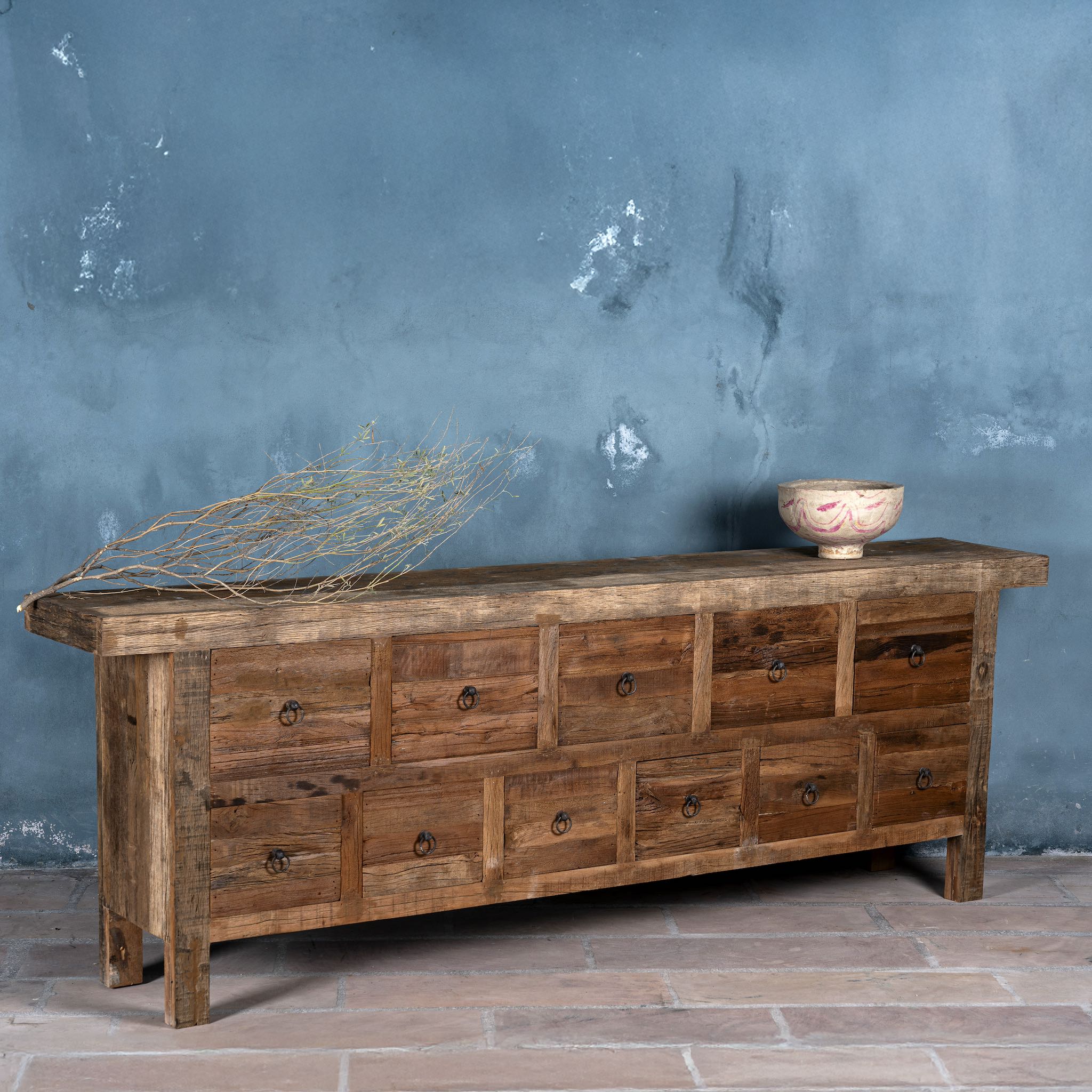 Side view image of a reclaimed wood console table with rustic finish, multiple drawers, and iron ring pulls; sustainable furniture with driftwood charm, 250 × 40 × 85 cm.