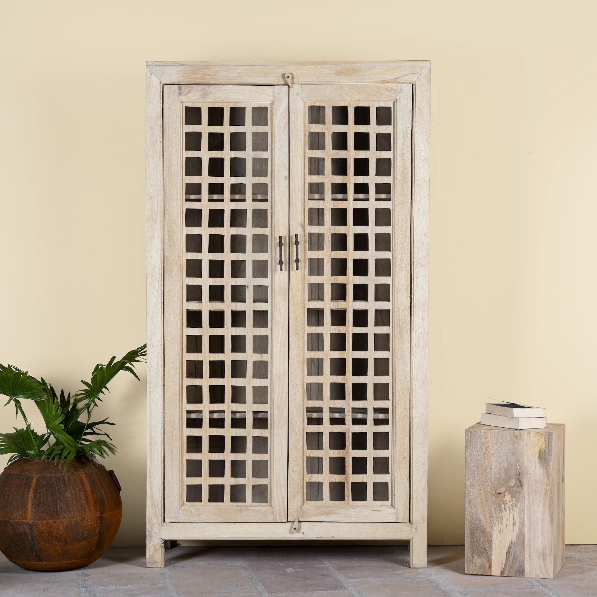 Sandblasted mango wood showcase with two glass-panelled grid doors and four interior compartments, finished in a light sun-washed tone, ideal as living room furniture.