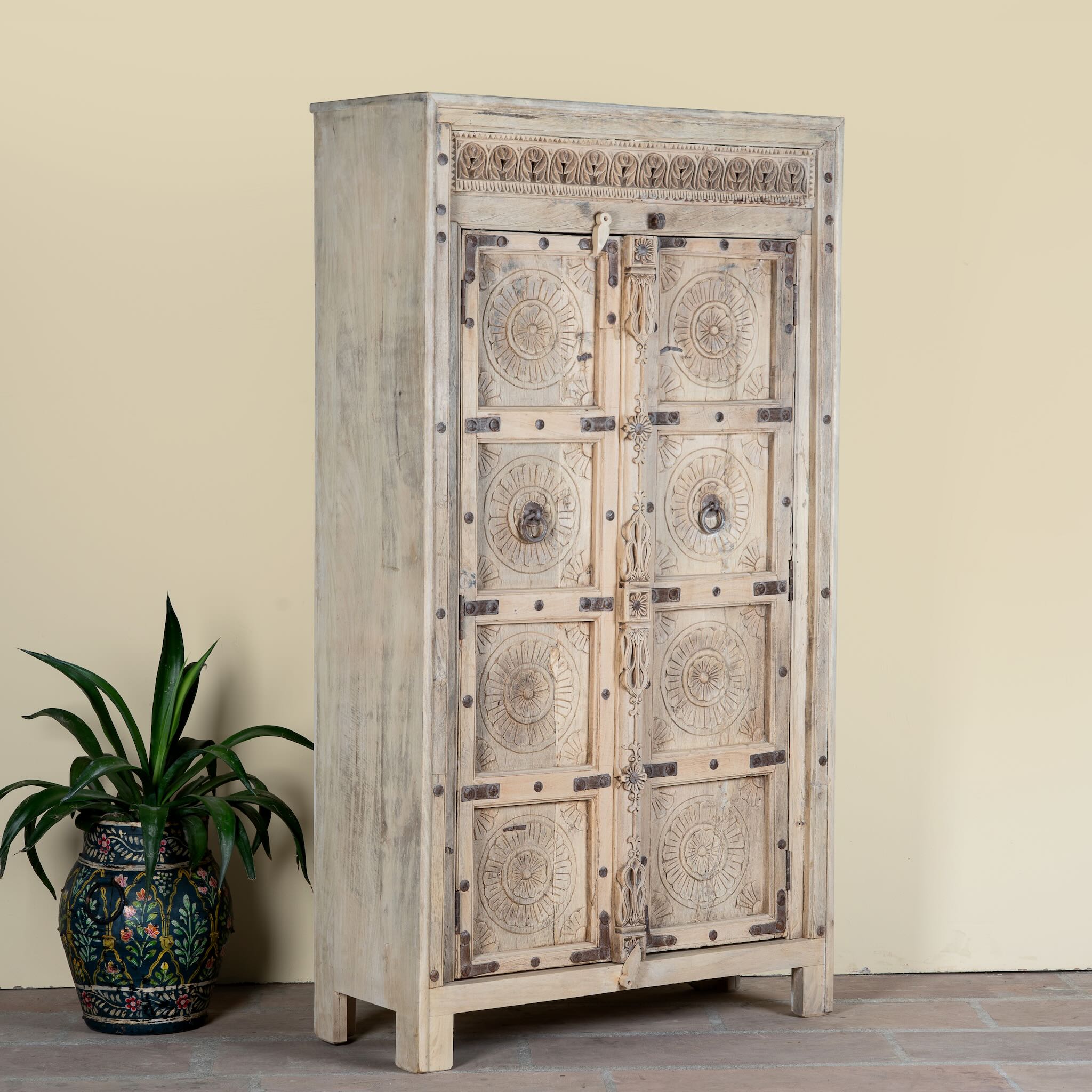 Side angle image of a reclaimed teak wood cabinet Elayna featuring an antique Indian door with carved motifs and iron accents. A unique piece of old door furniture in Mediterranean style, offering practical storage and historic charm.