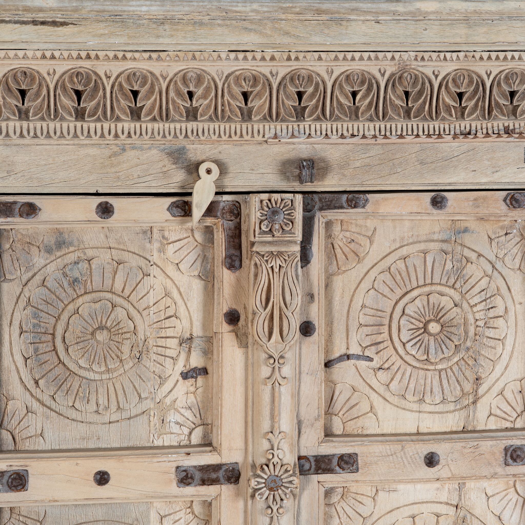 Close up image of a reclaimed teak wood cabinet Elayna featuring an antique Indian door with carved motifs and iron accents. A unique piece of old door furniture in Mediterranean style, offering practical storage and historic charm.