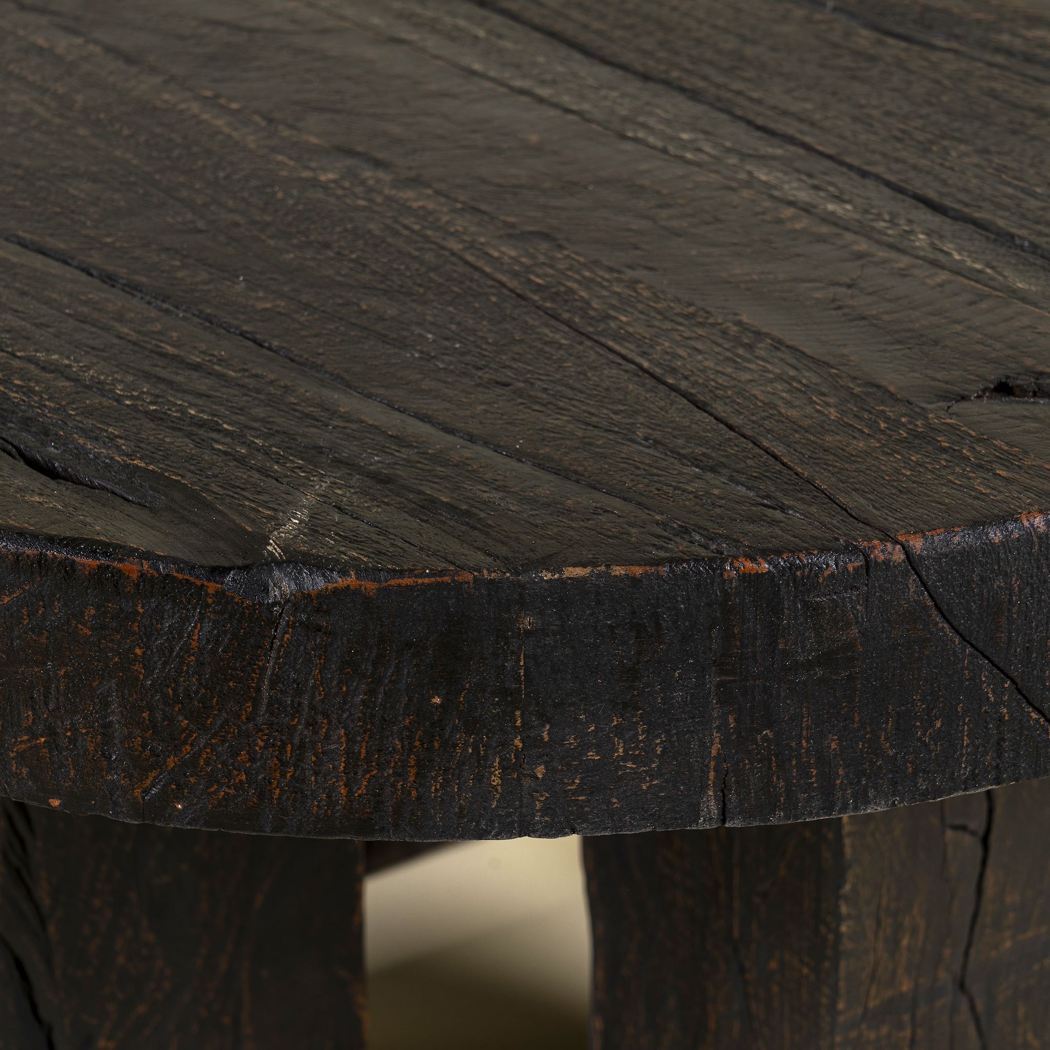 Close up picture of a rustic wood coffee table with round reclaimed teak top and black charred finish; sustainable furniture, 70 cm diameter, 40 cm height.
