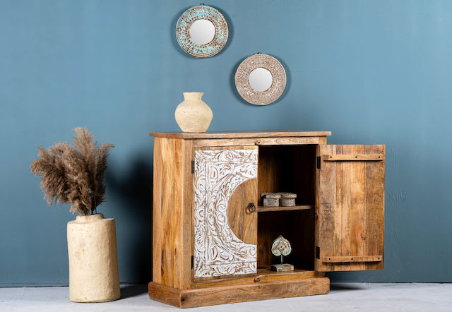 Side angle image with open doors of a carved wood furniture cabinet made from mango wood with floral whitewashed doors, 90 × 40 × 90 cm.
