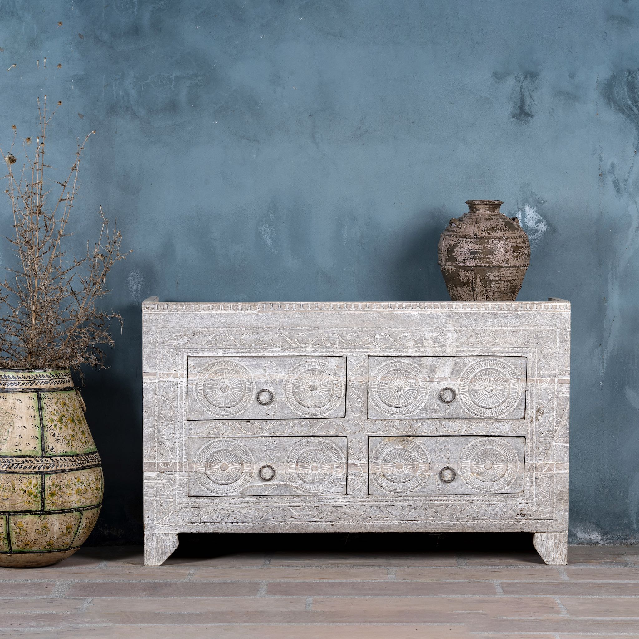 Ibiza style sideboard with six drawers, made from hand-carved wood in a whitewashed finish, featuring circular mandala motifs and rustic iron handles.