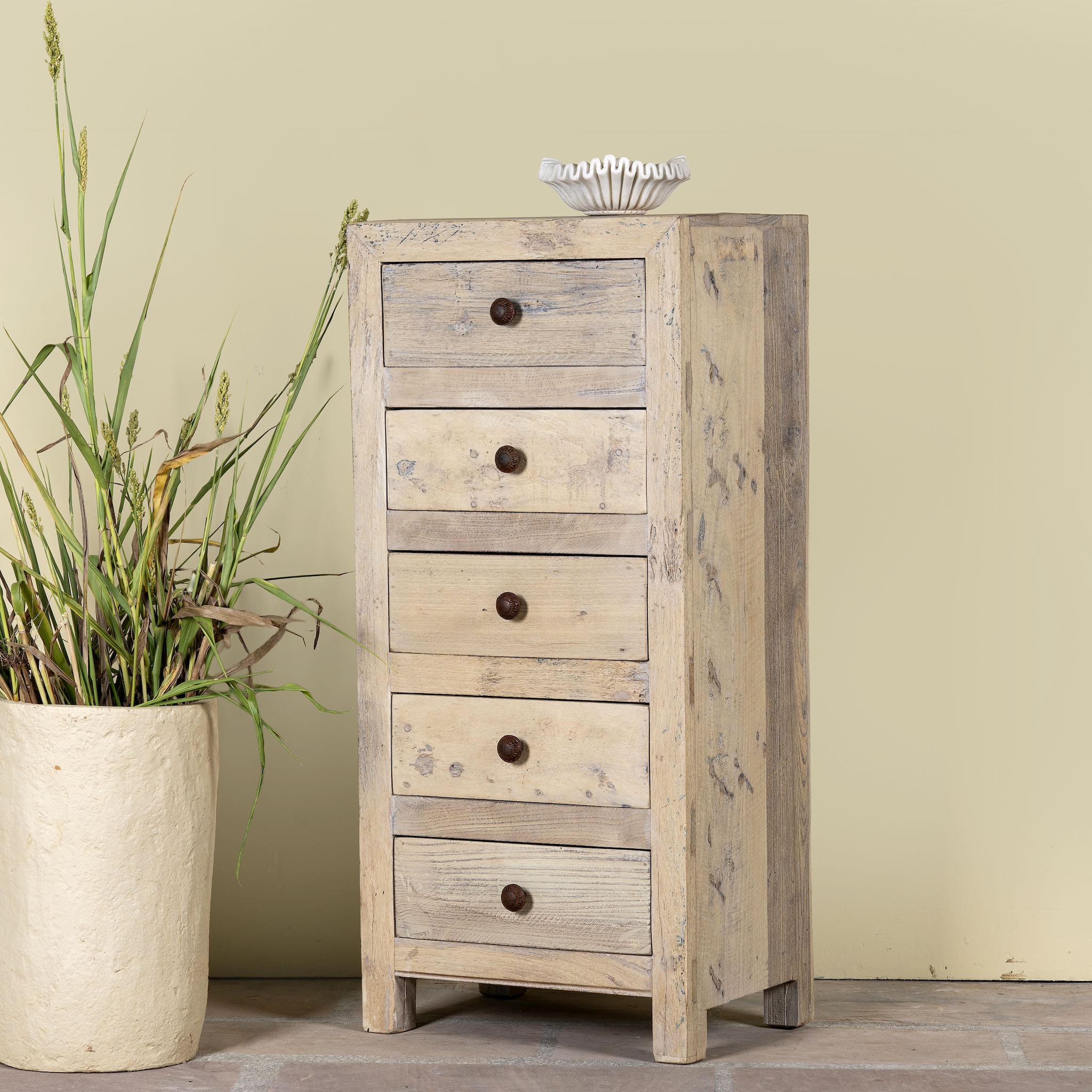 Side angle image of a chest of 5 drawers made from reclaimed wood with rustic finish; Ibiza style sustainable furniture, 50 × 35 × 110 cm.