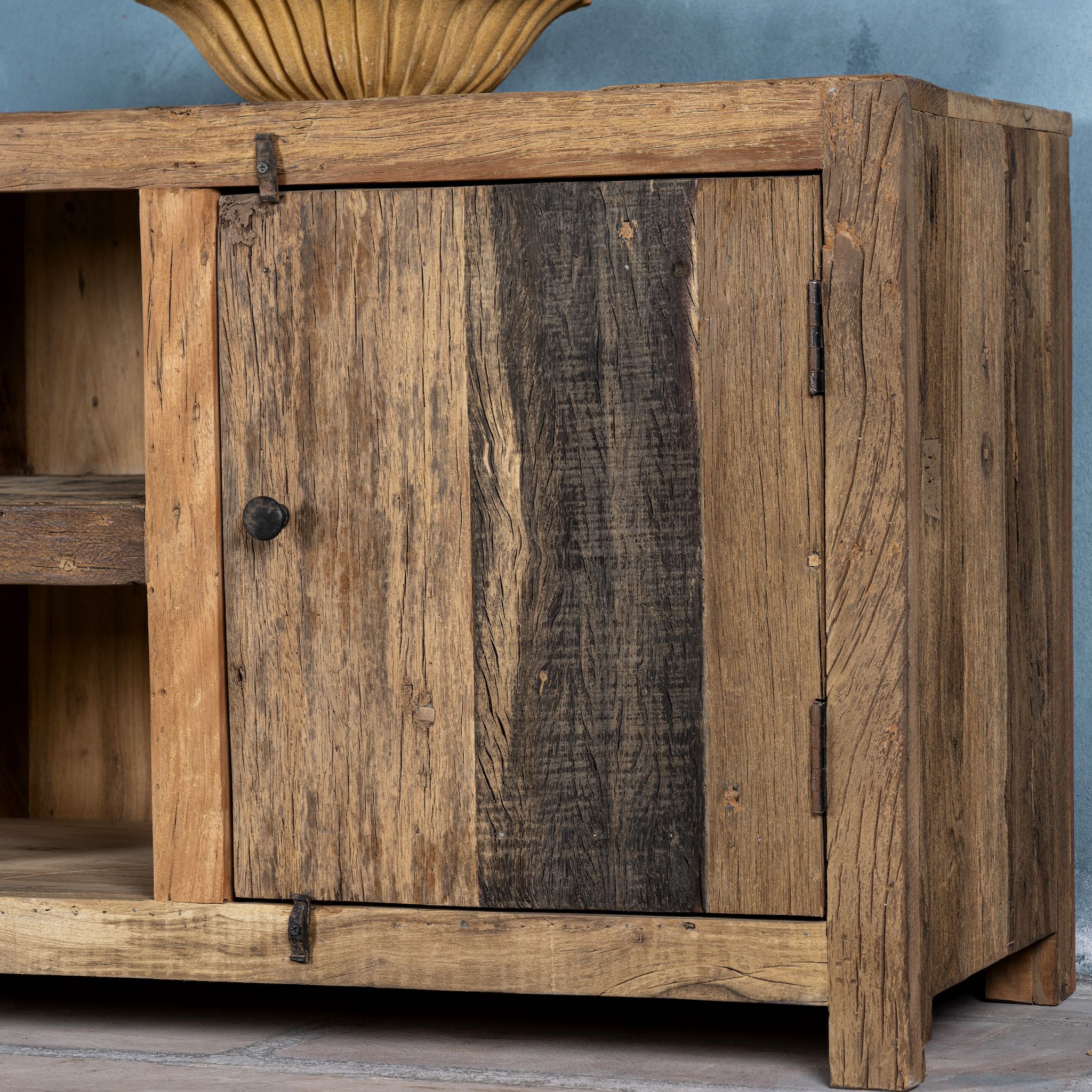Close up image of a driftwood lowboard made from reclaimed wood with two cabinets, open shelving, and rustic minimalist design, 150 × 40 × 60 cm.