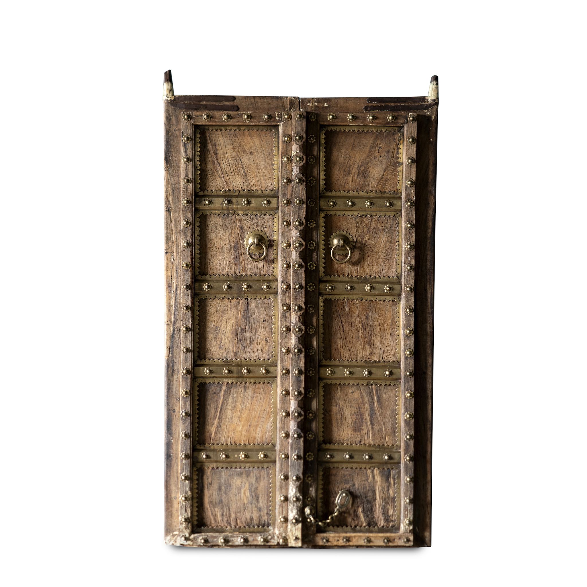 White background image antique Indian temple door made of old teak with original brass fittings, locks, and ring handles, featuring a richly aged patina from a historic Jain temple.