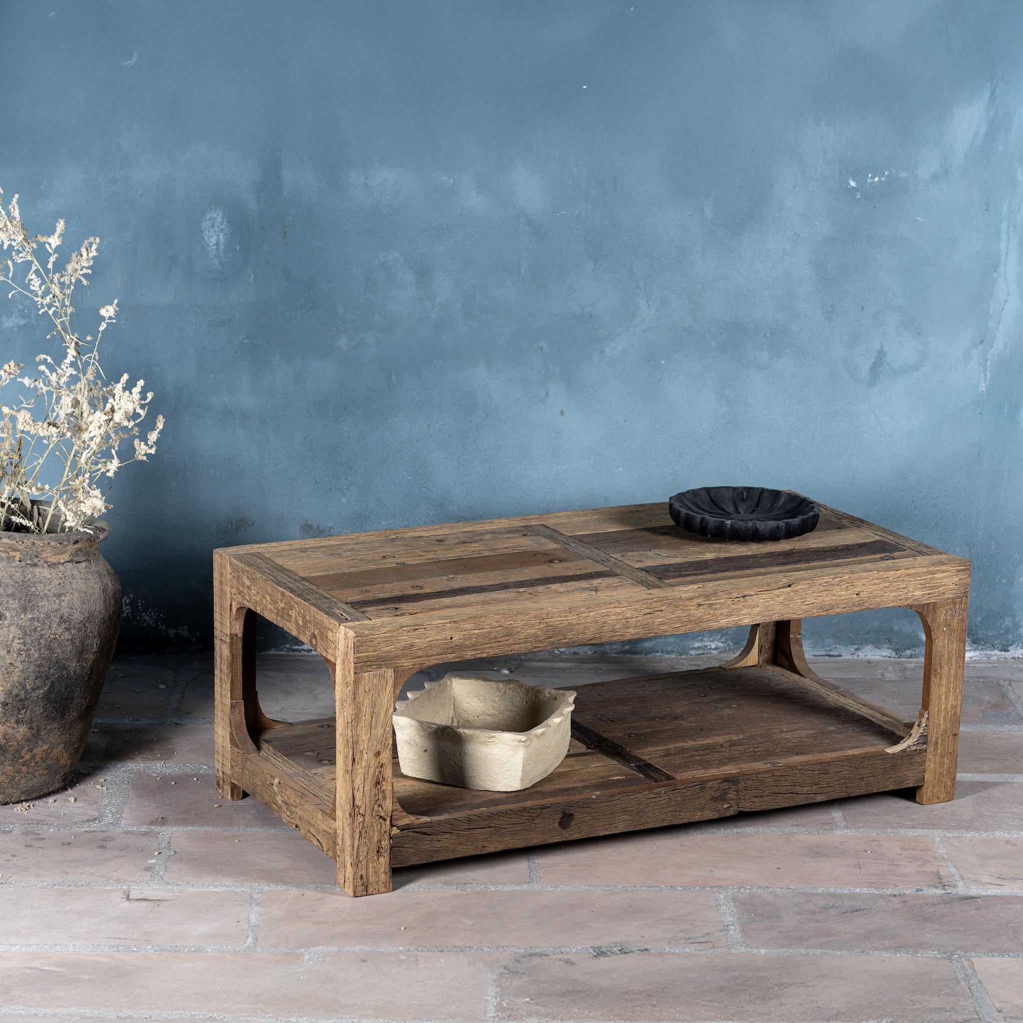 Side view of a driftwood coffee table made from reclaimed wood with rustic finish and open lower shelf; sustainable furniture, 120 × 60 × 40 cm.