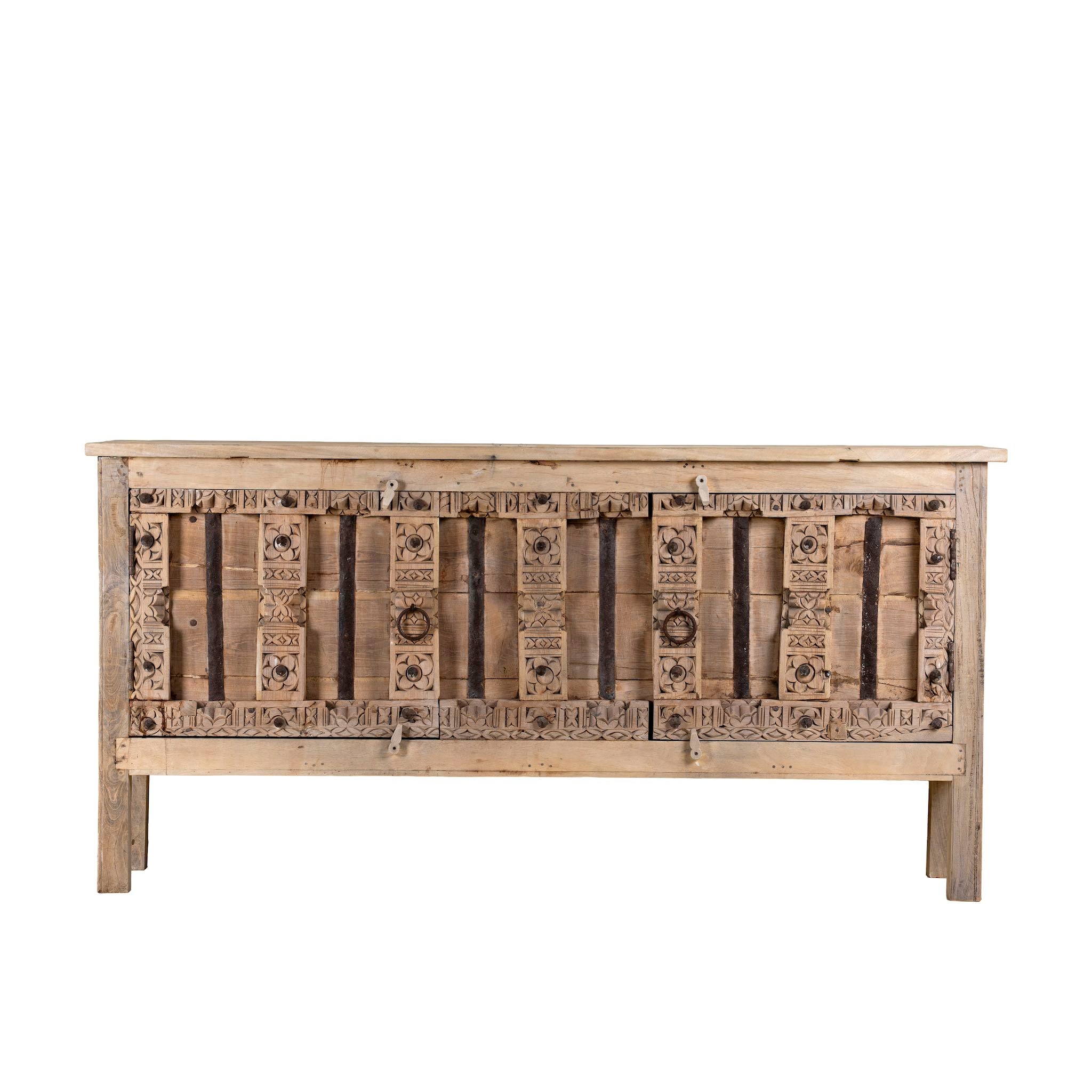 White background picture of a console table made from old teak door panels, featuring traditional hand-carved details, iron ring accents, and built-in storage in a natural rustic finish.