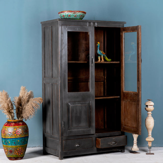 Side angle image with open door of a refurbished teak wood cabinet with shabby chic grey finish and glass-panelled doors – sustainable furniture for elegant living and dining spaces.