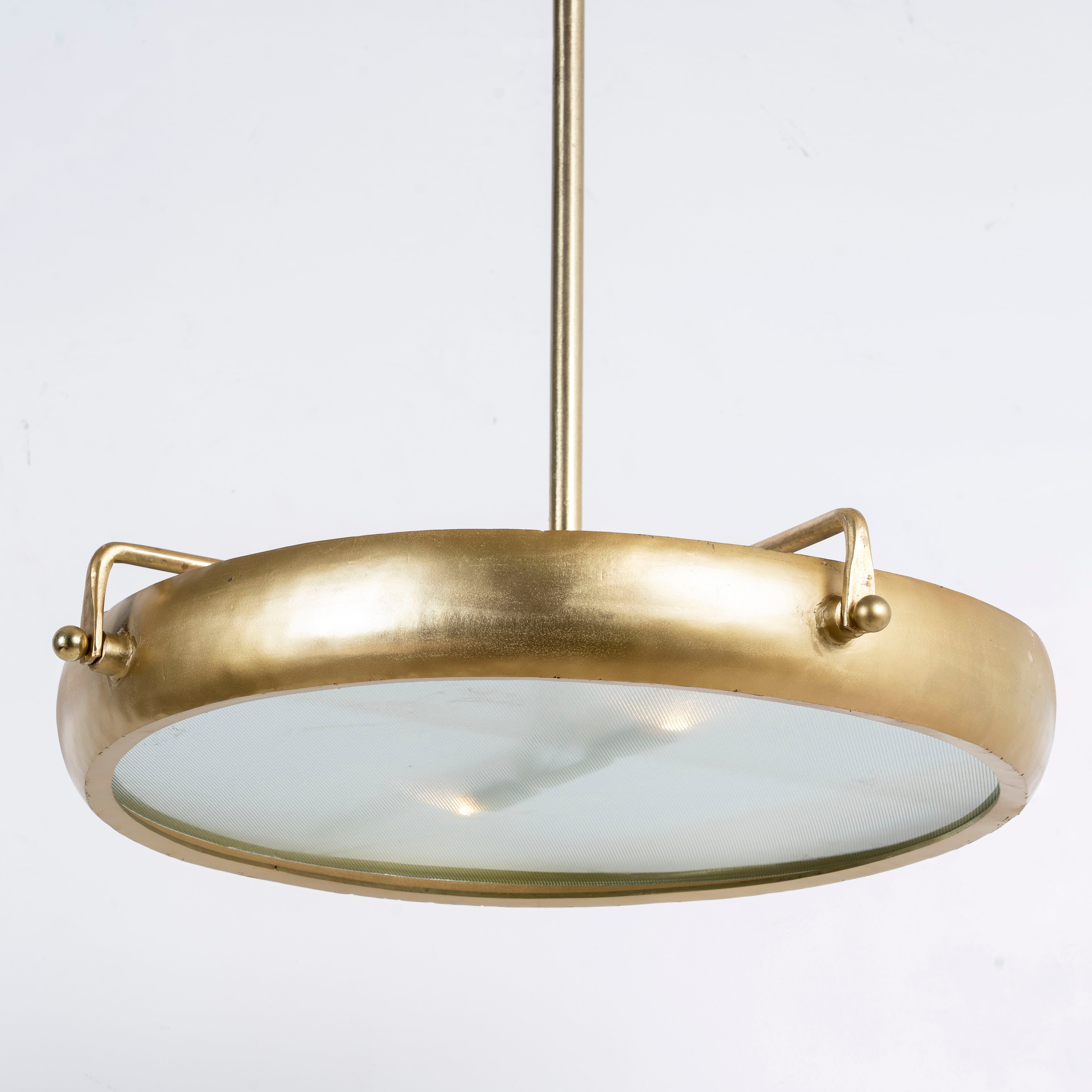 Side angle image of a extra-large round pendant lamp with clear glass and brass-plated iron frame – retro lighting and artsy lamp ideal for kitchens, dining rooms, or open living spaces.