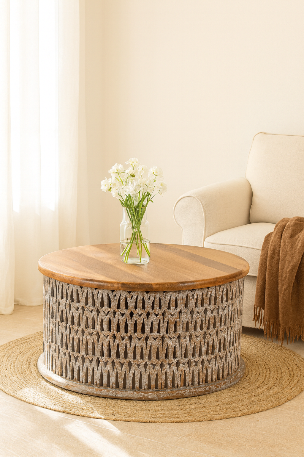 Lifestyle imagination of a round hand carved mango wood coffee table with white-washed base and natural wood top; 90 cm diameter, 45 cm height.