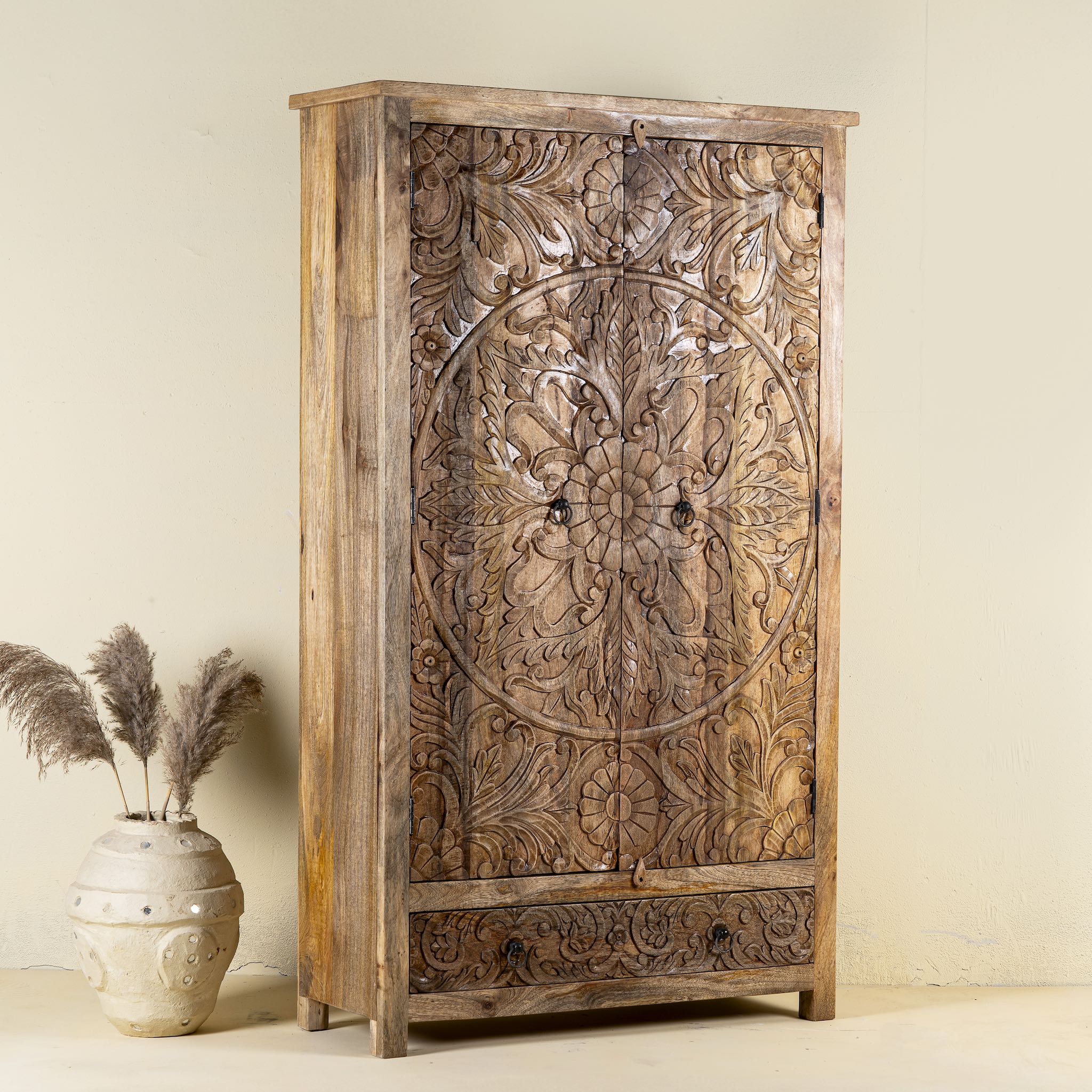 Side angle image of a Mango wood wardrobe with hand-carved floral detailing, Indian carved wooden furniture with bottom drawer, 105 × 40 × 180 cm.