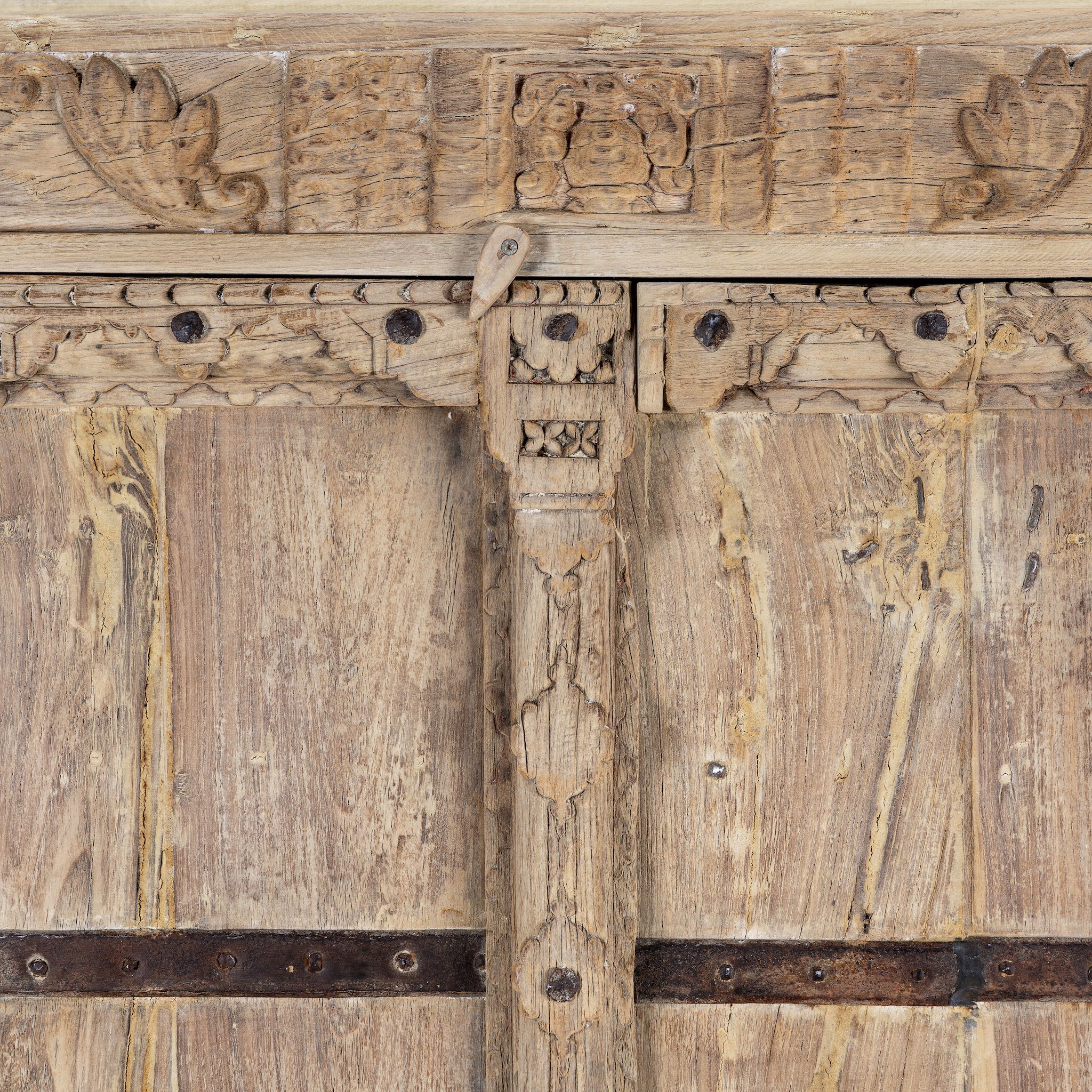 Close up image of a rustic solid wood wardrobe featuring vintage reclaimed door panels with iron accents and ring pull handles.
