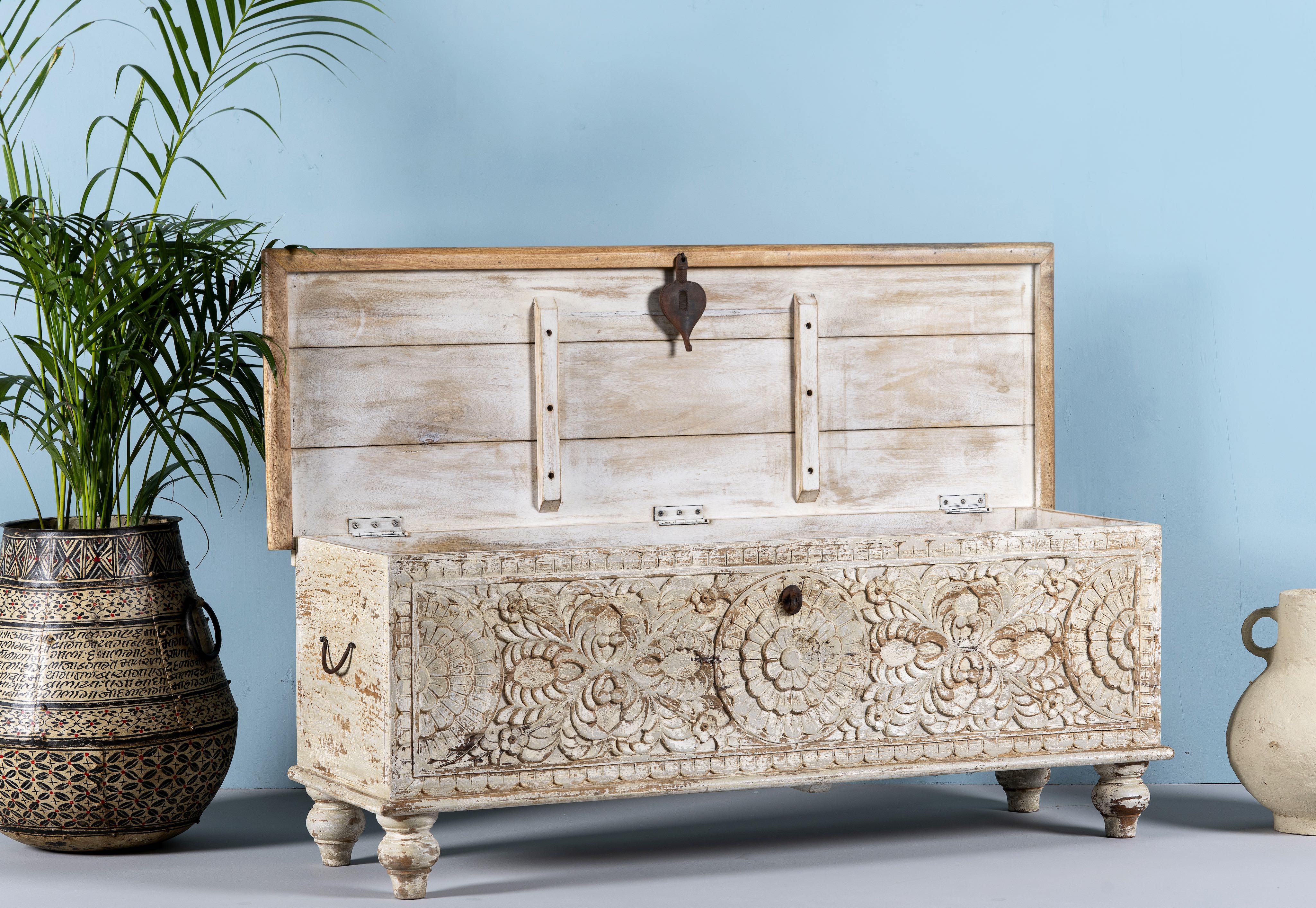 Side angle image with open lid of a Hand-carved mango wood chest box with floral motifs, whitewashed finish, and iron handles – vintage home accessory for rustic and elegant interiors.