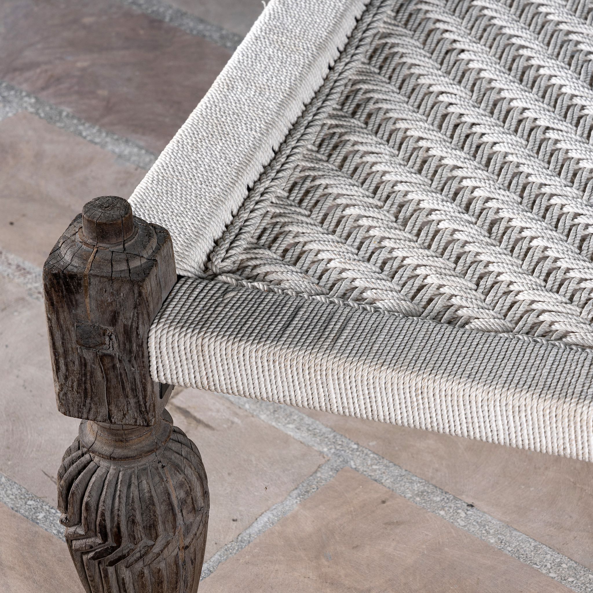 Close up image of a handwoven Indian Charpoi bed with reclaimed teak frame and carved legs; perfect for Indian home decor, 174 × 122 × 60 cm.