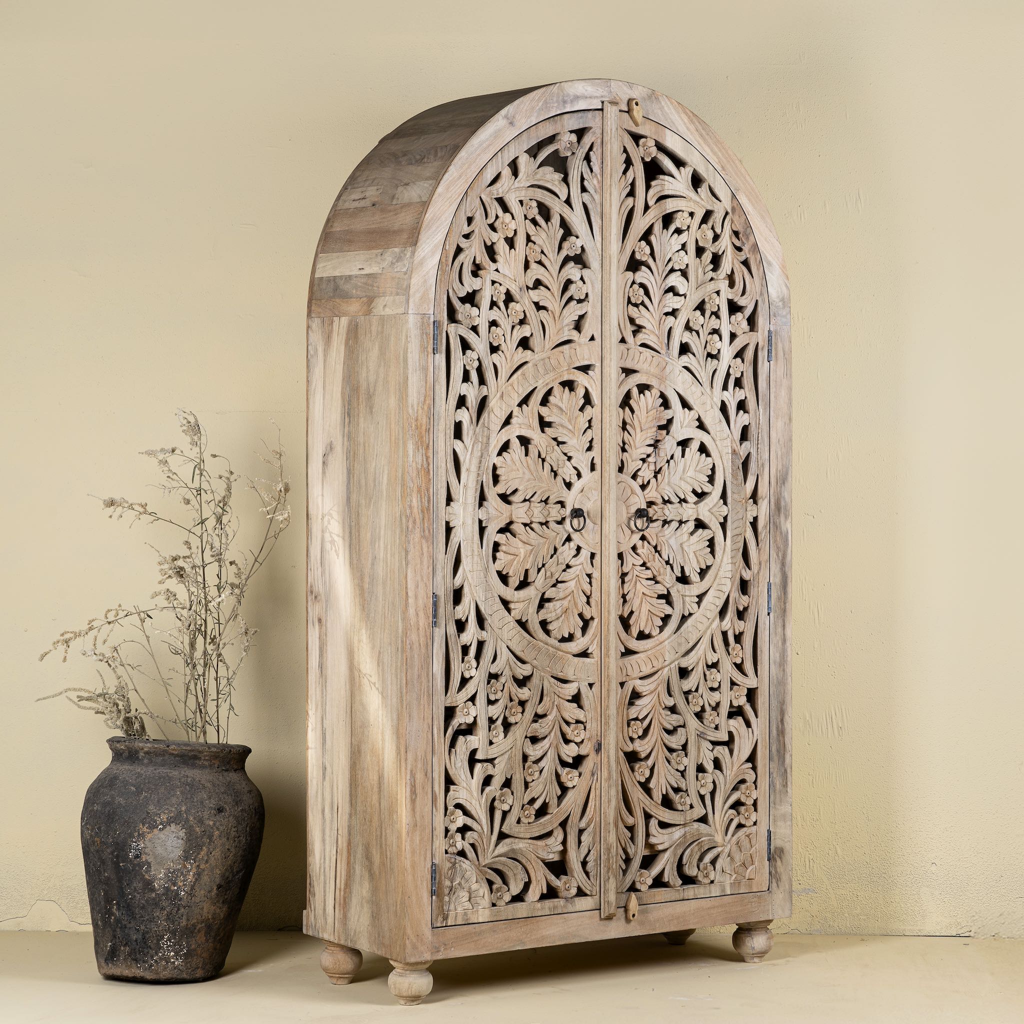 Side angle image of a hand-carved mango wood wardrobe, a statement piece of bedroom furniture ideal for a bohemian interior.