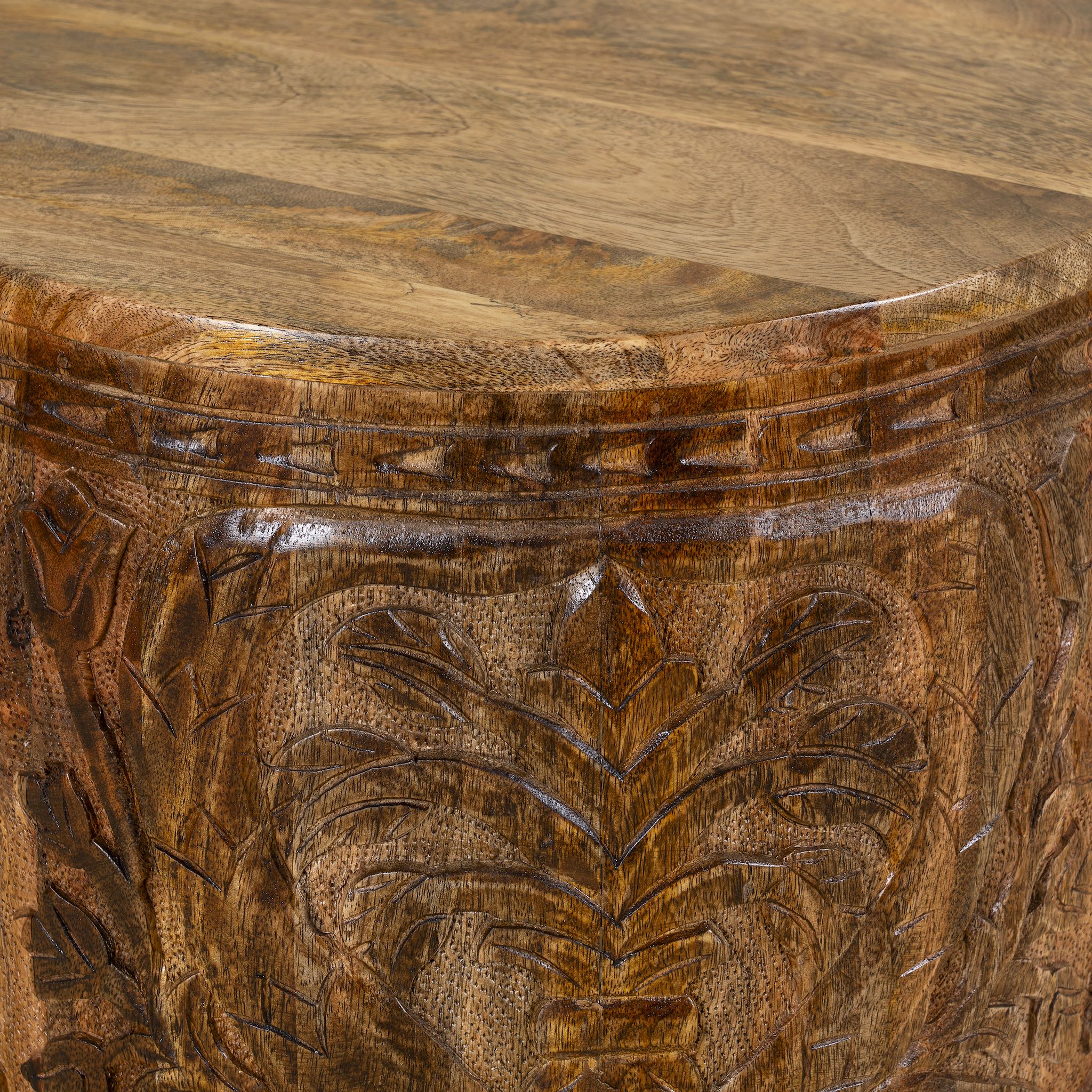 Close up picture of a round mango wood side table with hand carved floral design.