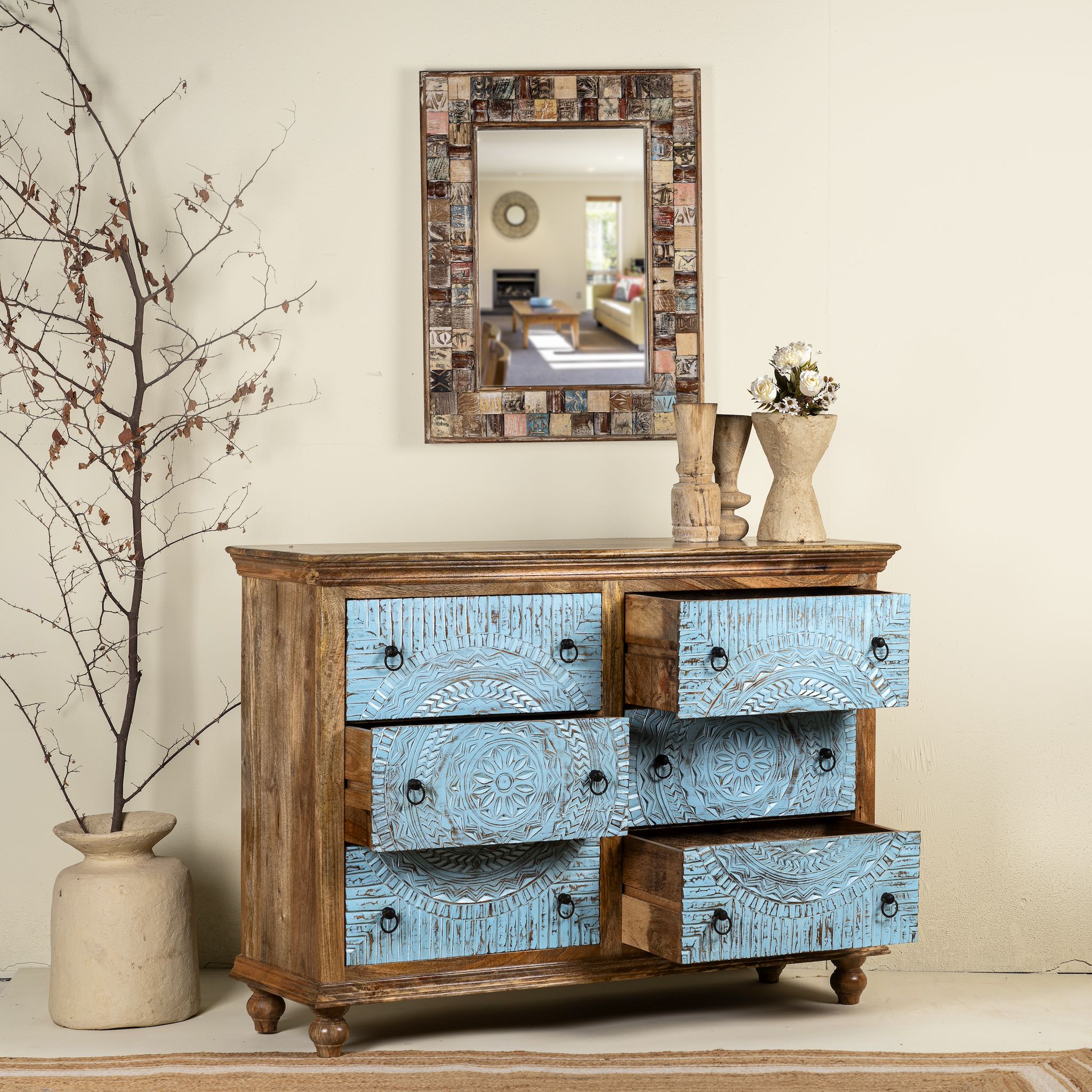 Image with open drawers of a hand-carved mango wood chest of drawers Safita with distressed blue finish and iron fittings, boho style living room furniture, 140 × 42 × 100 cm.