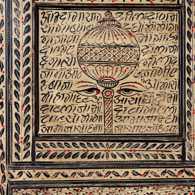 Close up image of a hand-painted display cabinet made from recycled wood with glass doors – sustainable furniture featuring Sanskrit motifs and traditional Indian craftsmanship.