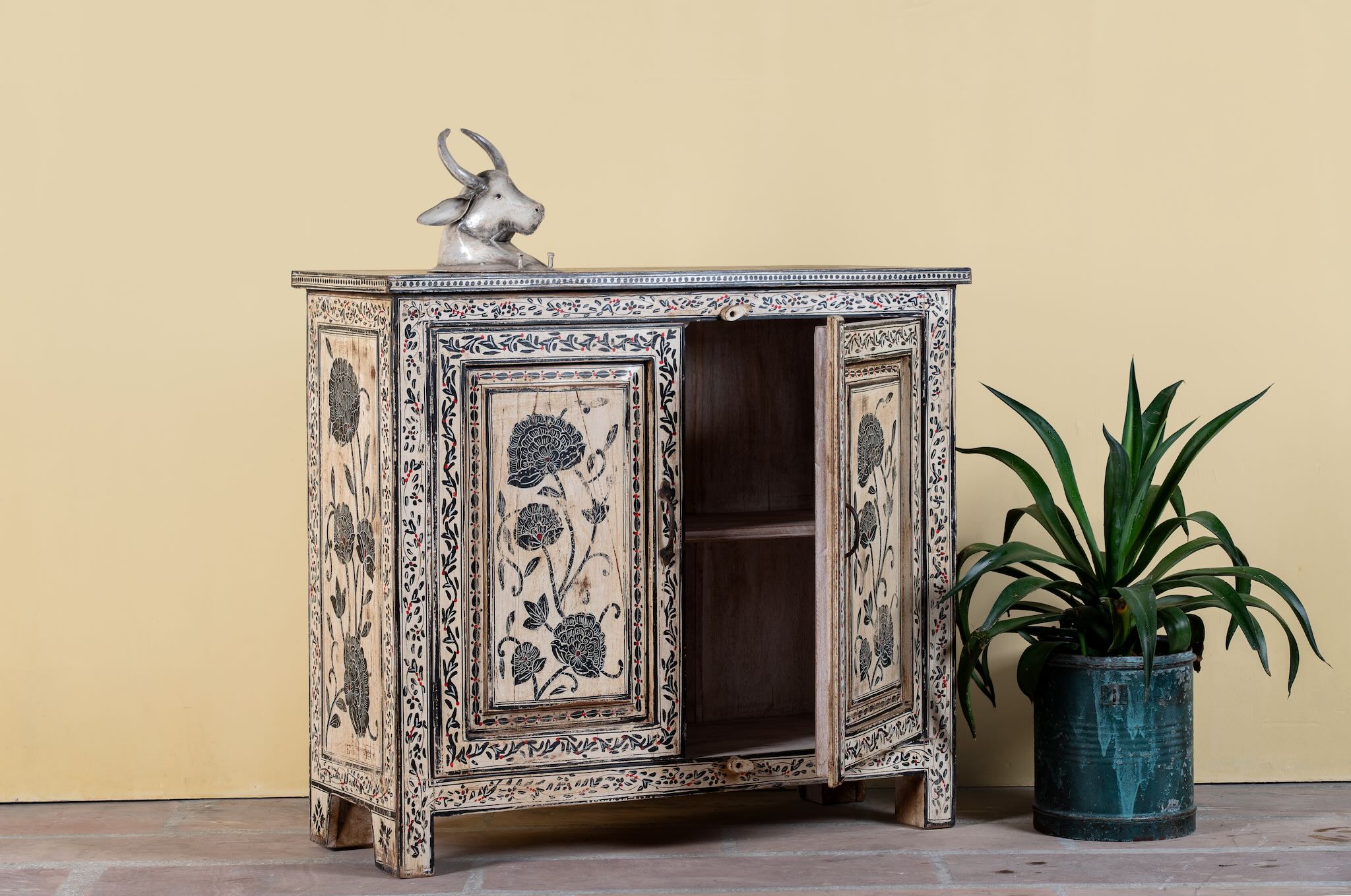 Side angle image with open door of a hand-painted cupboard made from reclaimed wood with Indian floral motifs; ideal for boho chic living room or unique furniture decor, 100 × 92 × 36 cm.