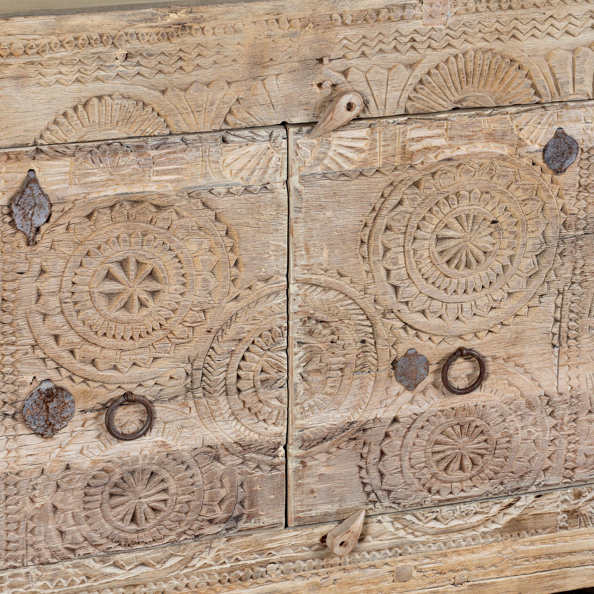 Close up image of a sideboard Taksh made from reclaimed teak wood, featuring carved antique Indian door fronts with circular mandala motifs. A unique piece of old door furniture combining Mediterranean style with traditional Indian craftsmanship.