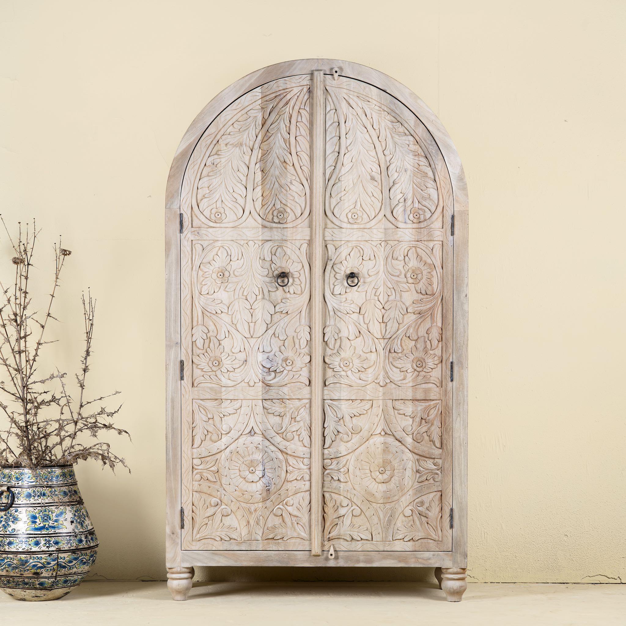 Handcrafted mango wood wardrobe with arched top and floral carving – Tamia by Om Home & Garden, unique furniture with Ibiza-style charm for living rooms and bedrooms.