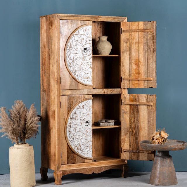 Side angle image with open doors of a mango wood wardrobe with hand-carved floral front, vintage carved wood furniture with curved legs, 180 × 90 × 40 cm.