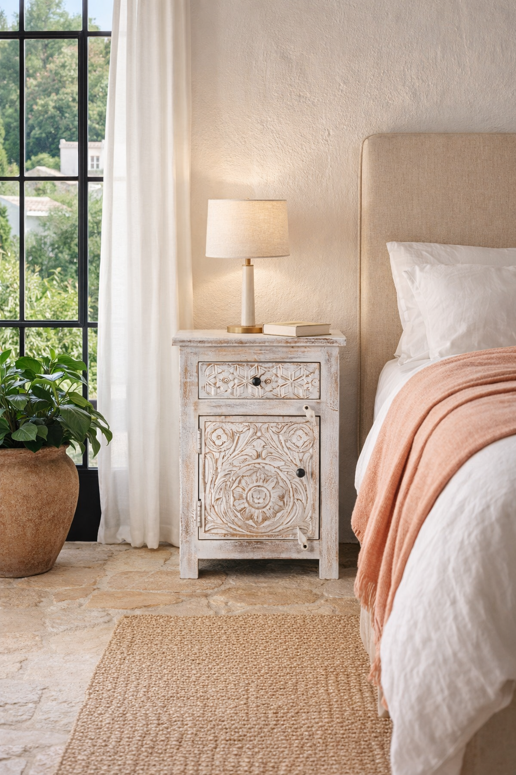 Lifestyle imagination of a pair of mango wood nightstands Uday with whitewashed vintage finish, featuring hand-carved geometric and floral designs. Each bedside table includes a drawer and cabinet for elegant and practical storage.