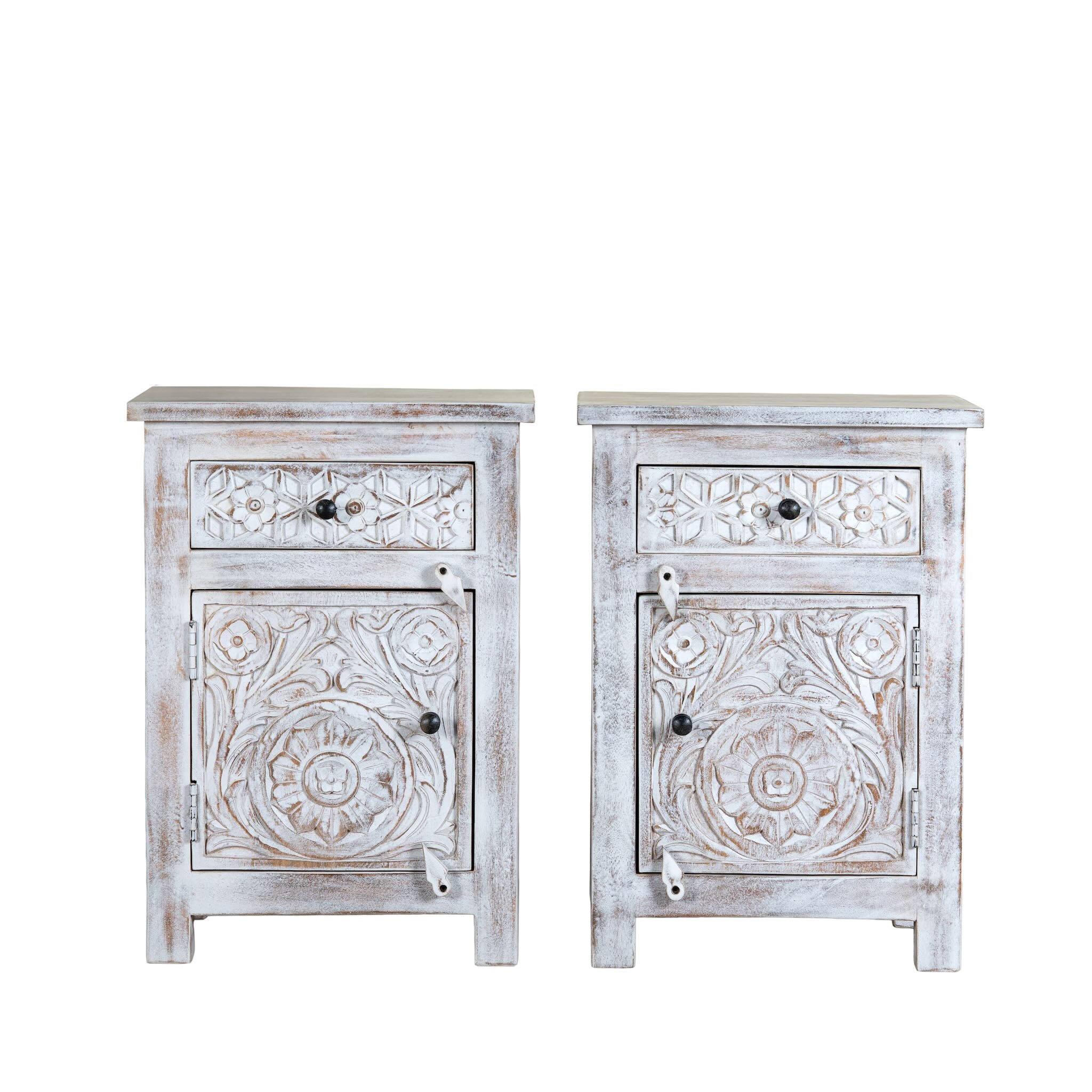 White background image of a pair of mango wood nightstands Uday with whitewashed vintage finish, featuring hand-carved geometric and floral designs. Each bedside table includes a drawer and cabinet for elegant and practical storage.