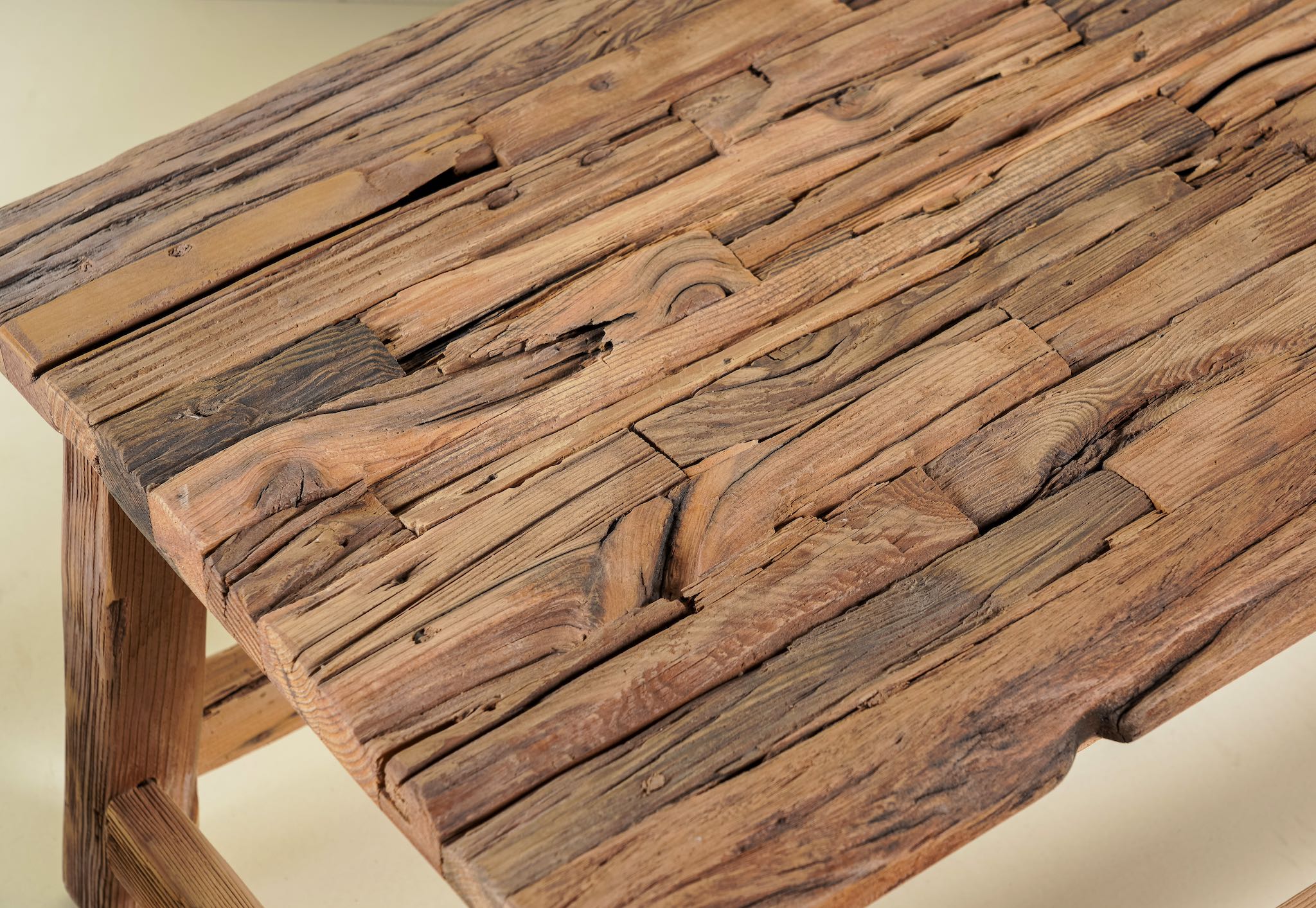 Close up image of a rustic driftwood coffee table made from reclaimed wood with sandblasted finish; sustainable furniture, 100 × 50 × 45 cm.