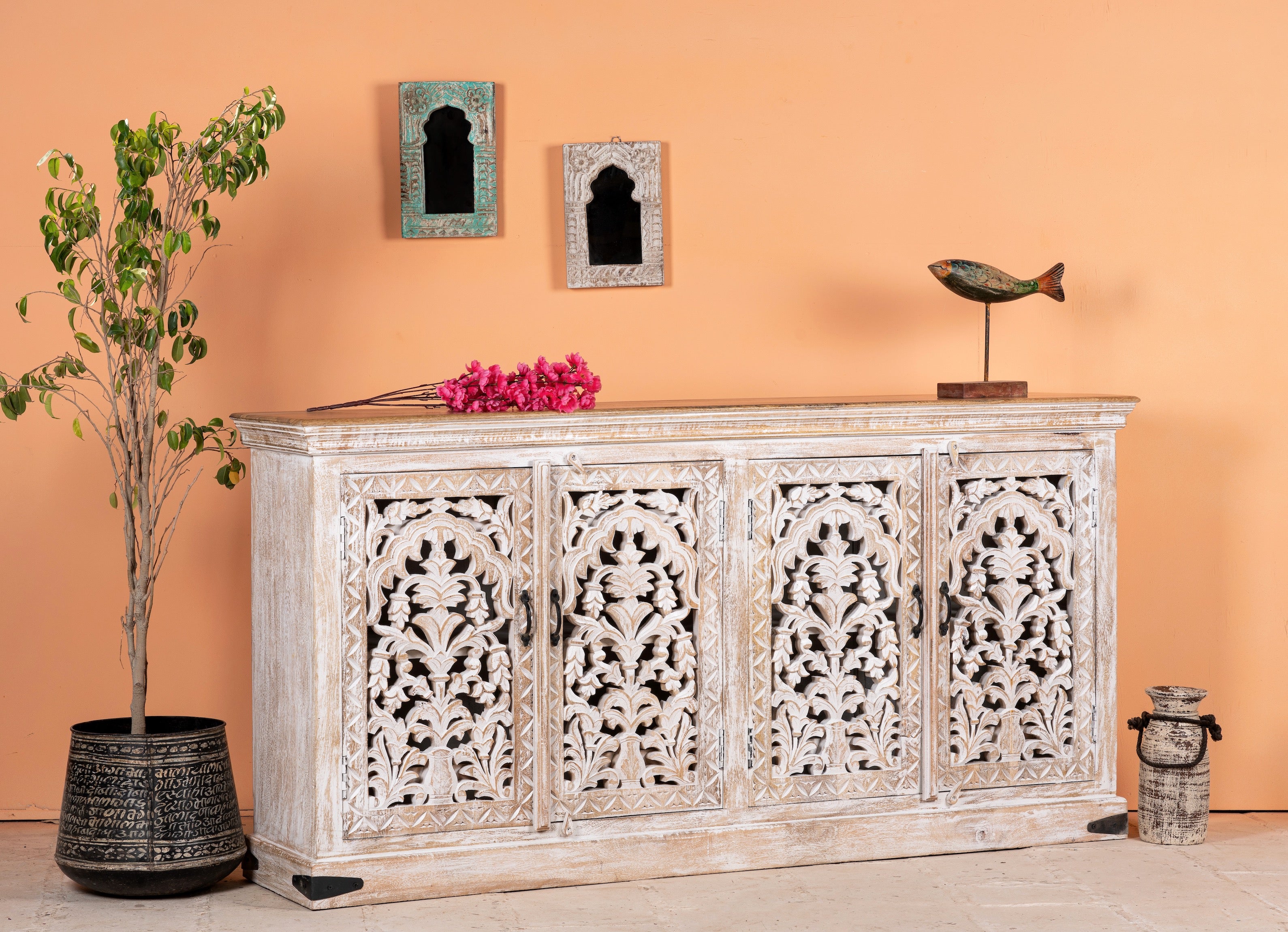 Side angle image of a hand-carved whitewashed mango wood sideboard with intricate floral detailing, perfect for a boho chic living room or vintage-inspired interior.