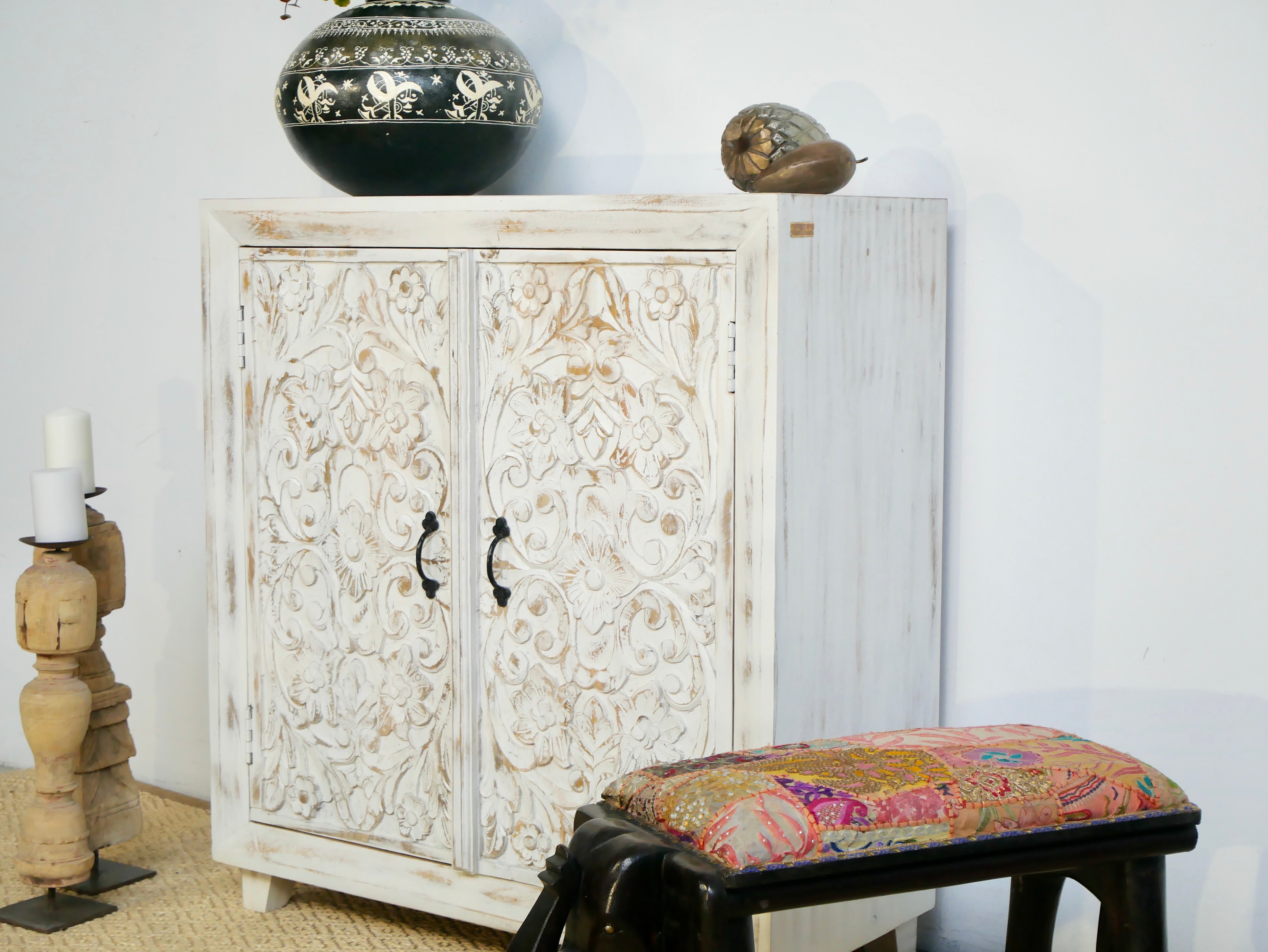 Side angle image of a white washed wooden cabinet made from mango wood with hand-carved Indian floral patterns, rustic Mediterranean-style furniture, 90 × 97 × 40 cm.