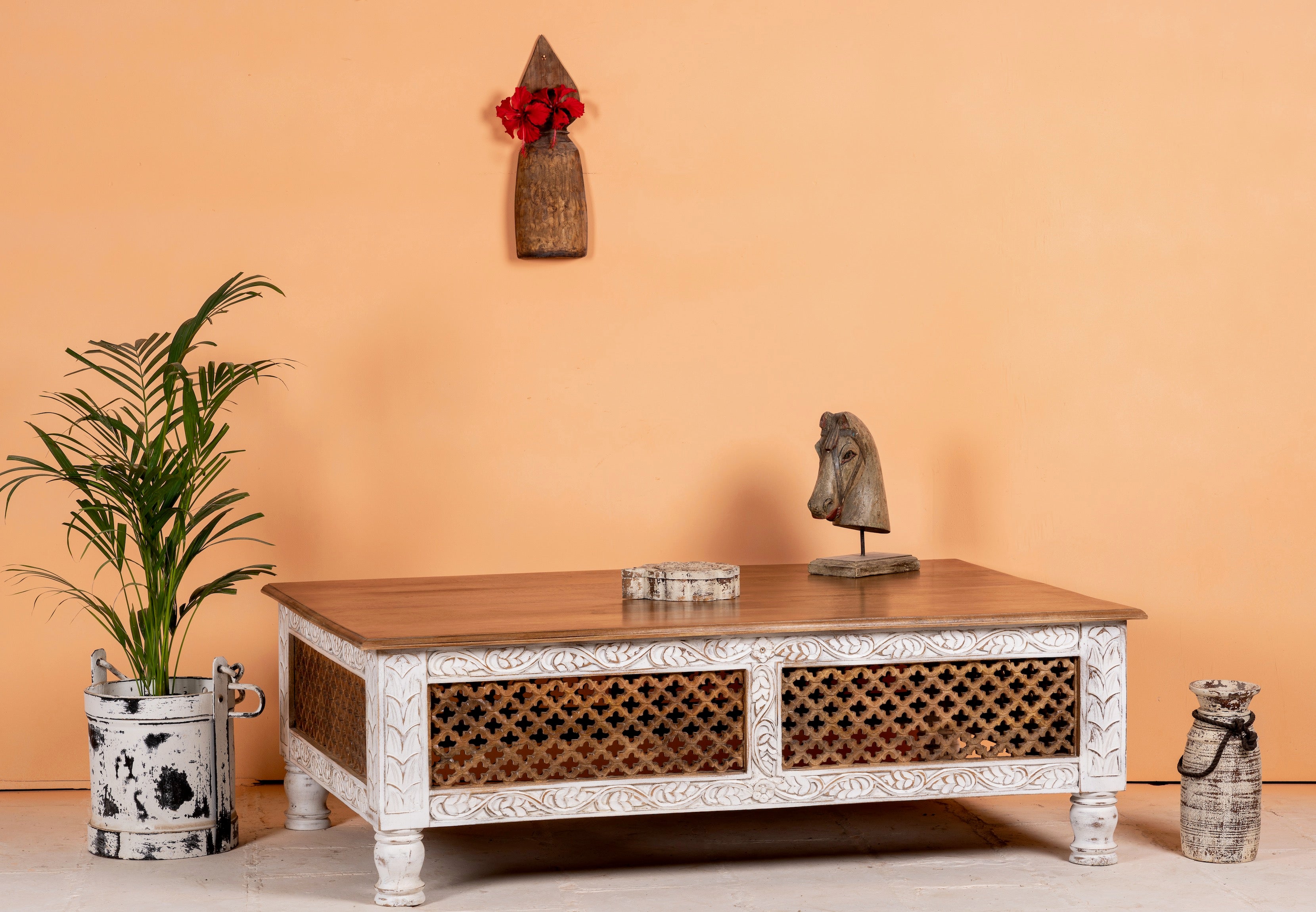 Side angle image of a hand carved mango wood coffee table with floral frame detailing; rustic natural finish, 140 × 90 × 46 cm.